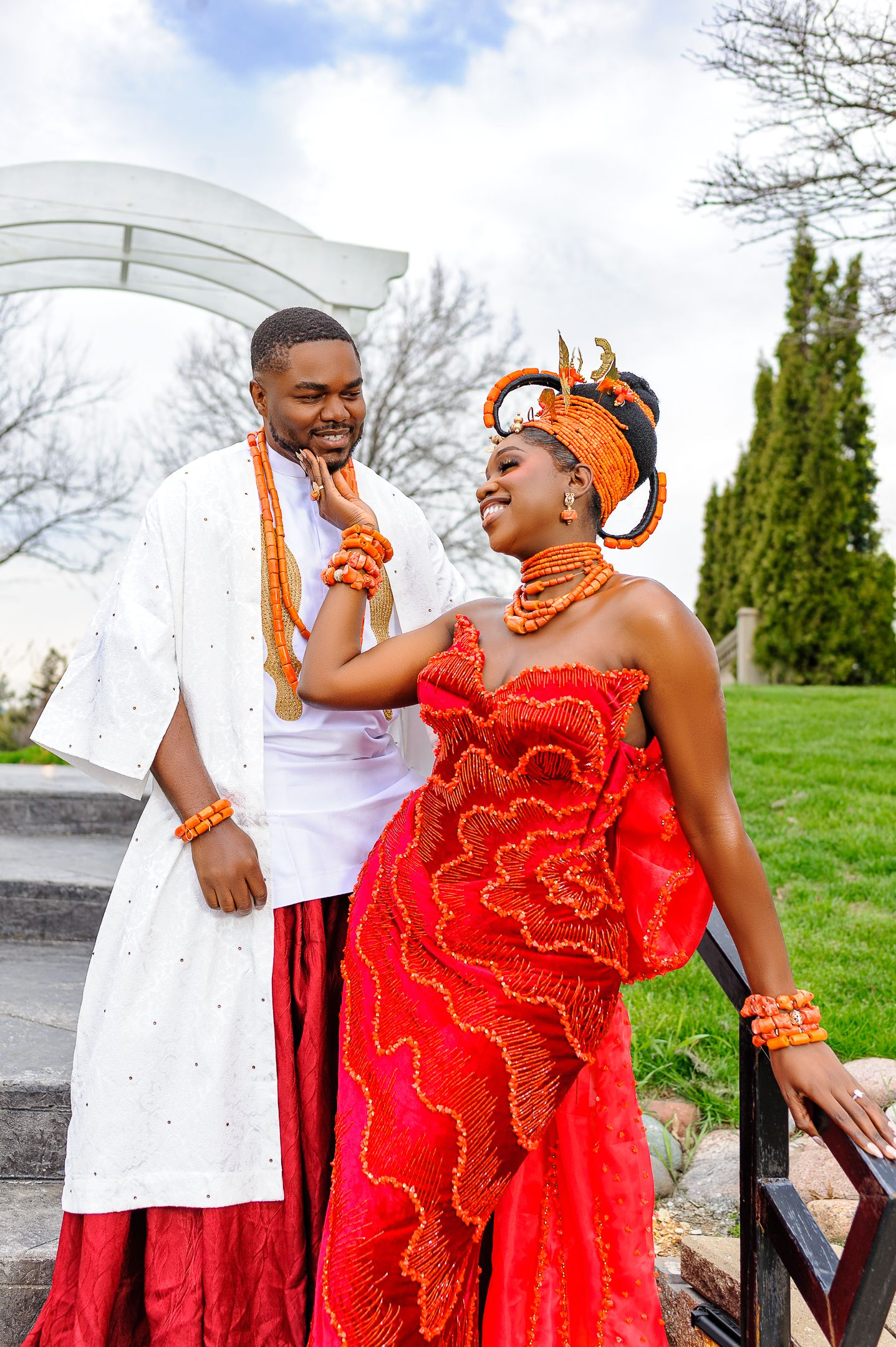 Nigerian couple in traditional wedding attire sharing a joyful moment, wearing coral beads and colorful outfits.