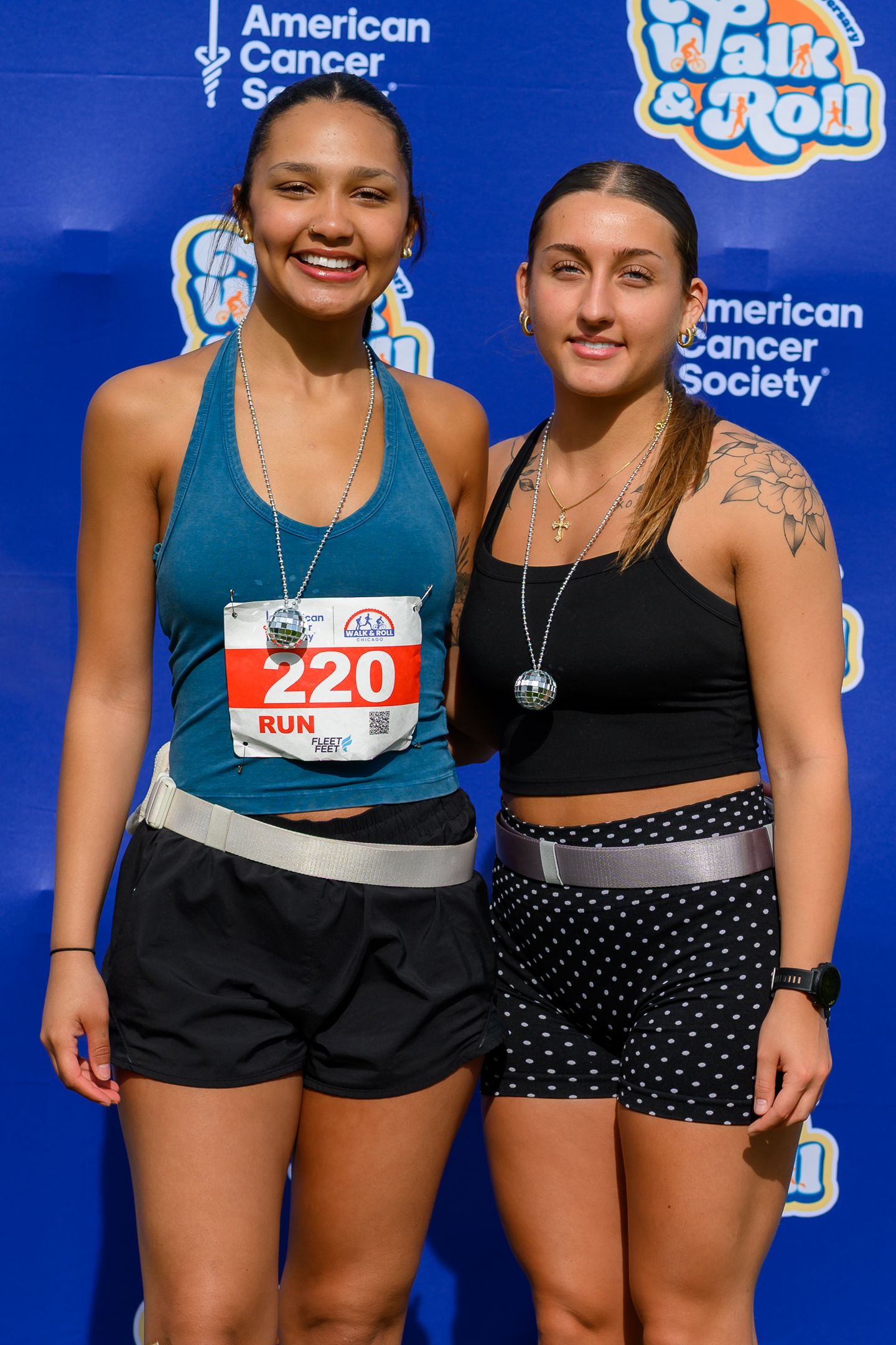 Two young women with race bibs smiling at American Cancer Society Walk and Roll Chicago event.