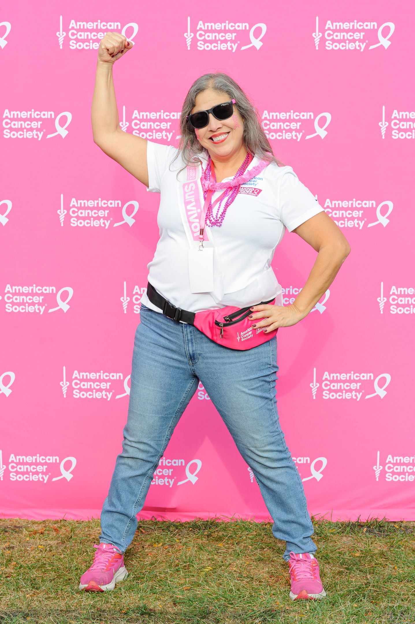 Energetic dance poses captured against pink American Cancer Society step-and-repeat banner.