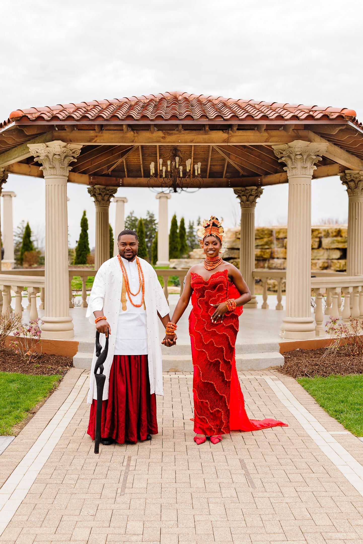 Nigerian bride and groom in traditional Urhobo wedding attire posing in front of elegant gazebo.