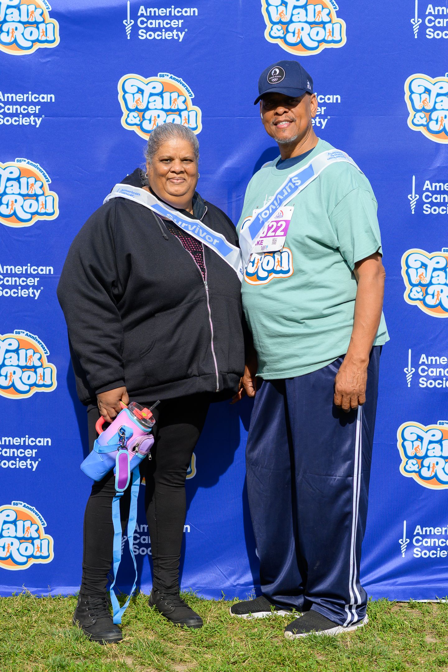 Two participants posing at American Cancer Society Walk and Roll event, woman wearing survivor sash.