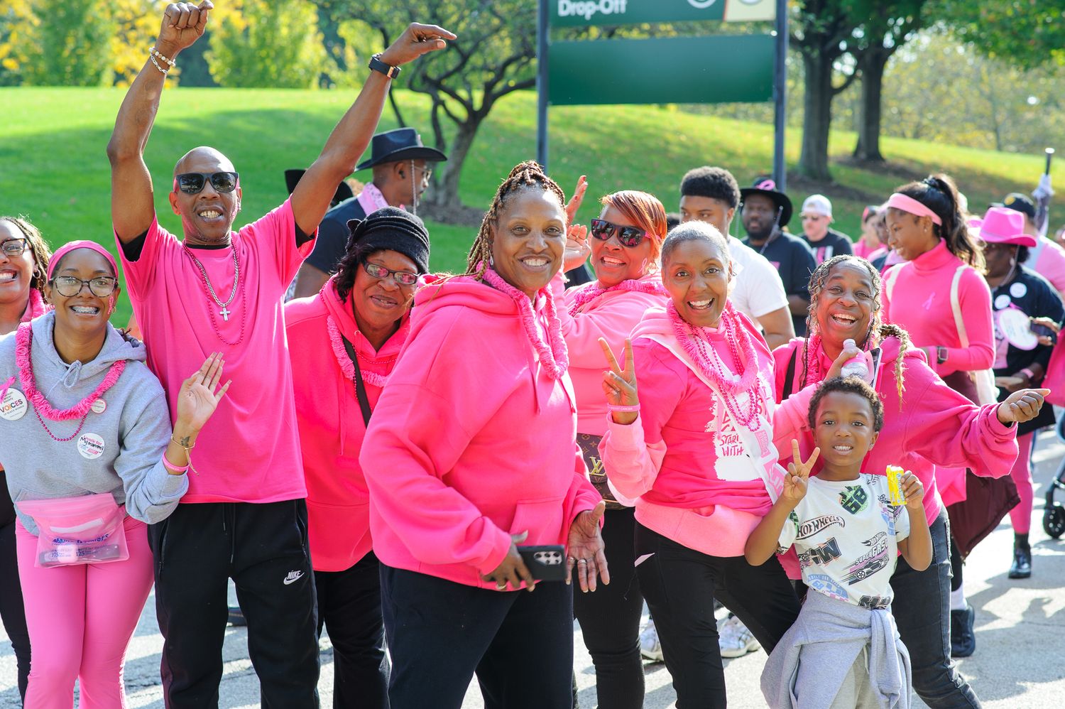 Large group of participants wearing bright pink shirts gather outdoors for a charity walk or run event.