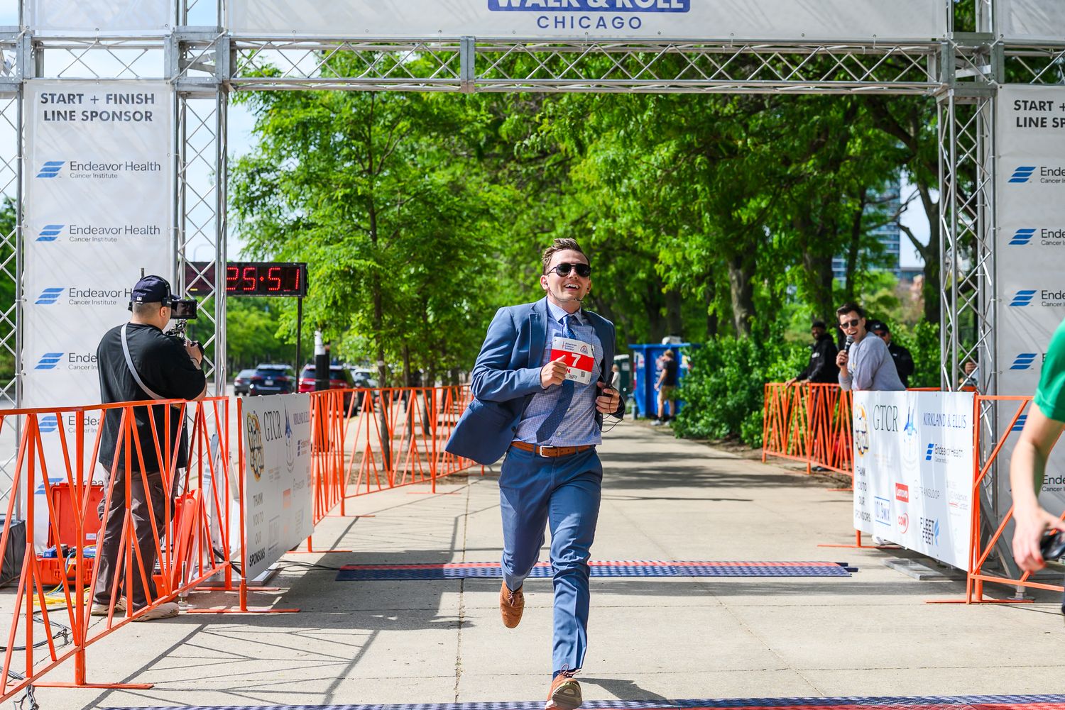 Man in blue suit crosses finish line at American Cancer Society Walk & Roll Chicago charity race event.