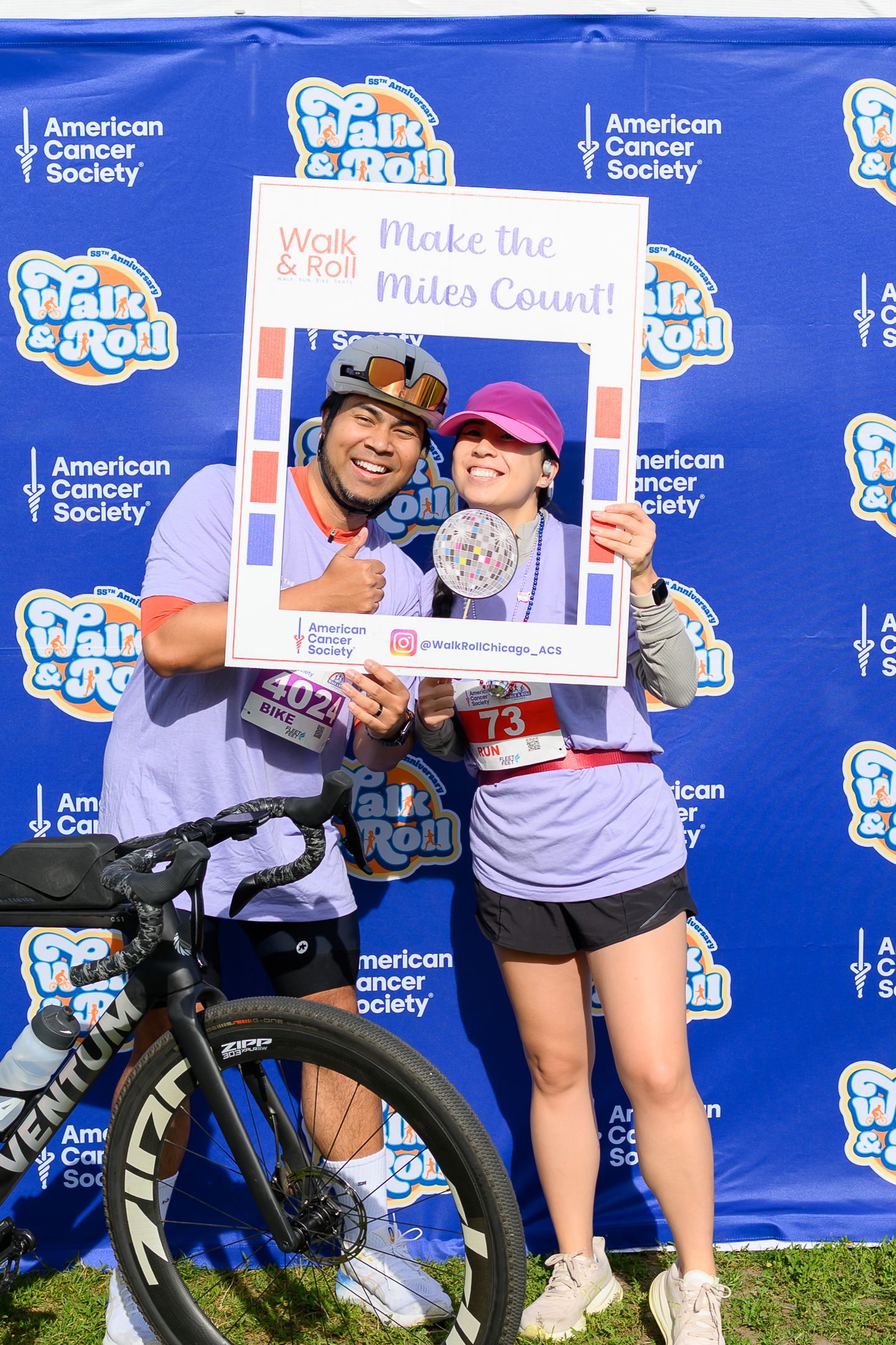 Couple poses with Walk & Roll Make the Miles Count frame at American Cancer Society charity event.