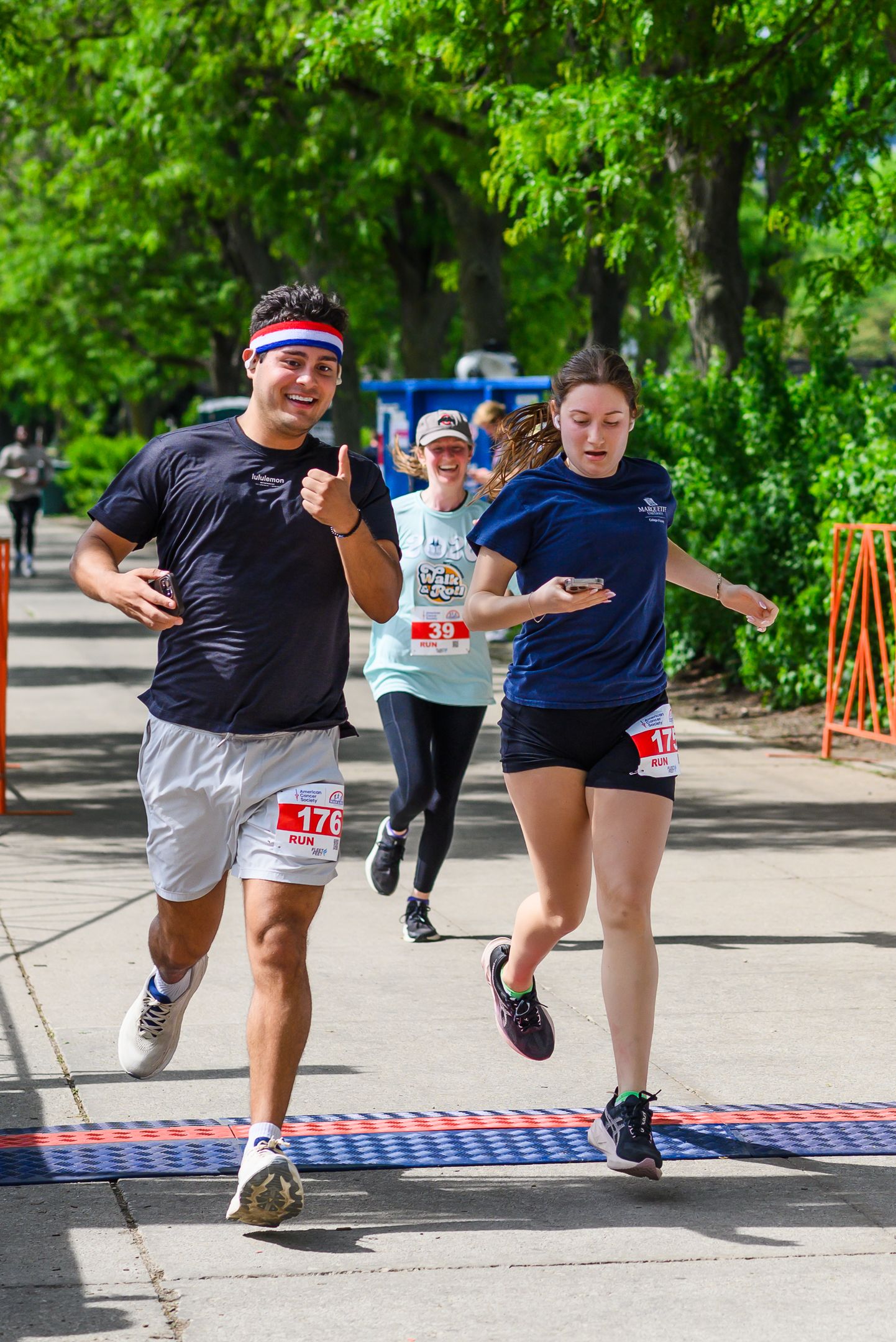 Three runners crossing finish line at American Cancer Society Walk & Roll charity event.