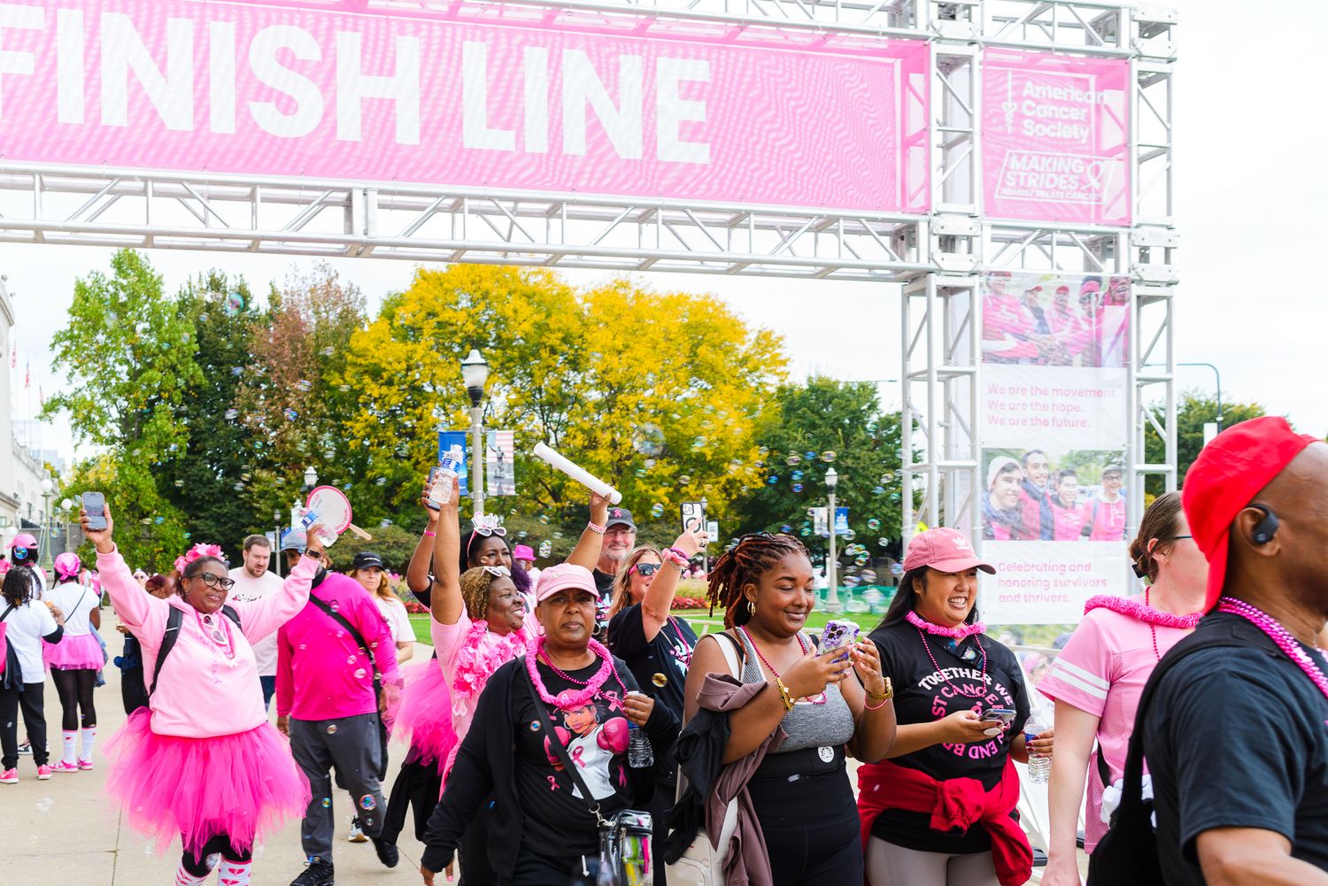 Participants walk along a race course with pink banners and decorations during a breast cancer awareness event.