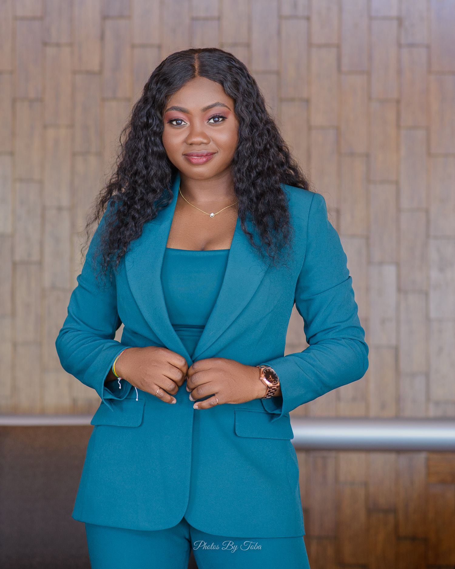 Professional wearing a stylish teal blue business suit poses confidently against a textured wall background.