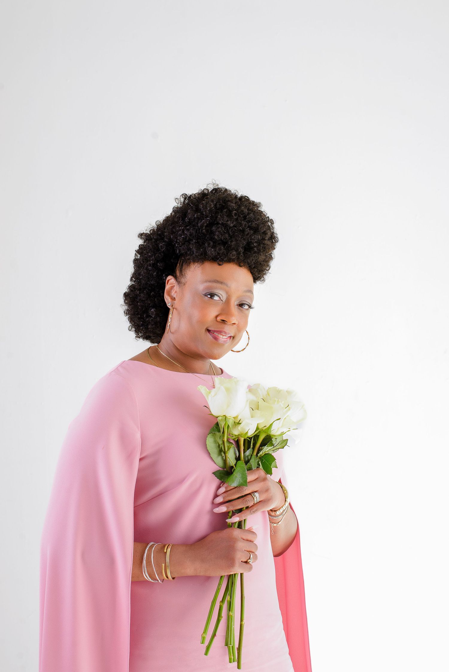 Person in pink sweater holds white flowers while posing against white background in three sequential photos.