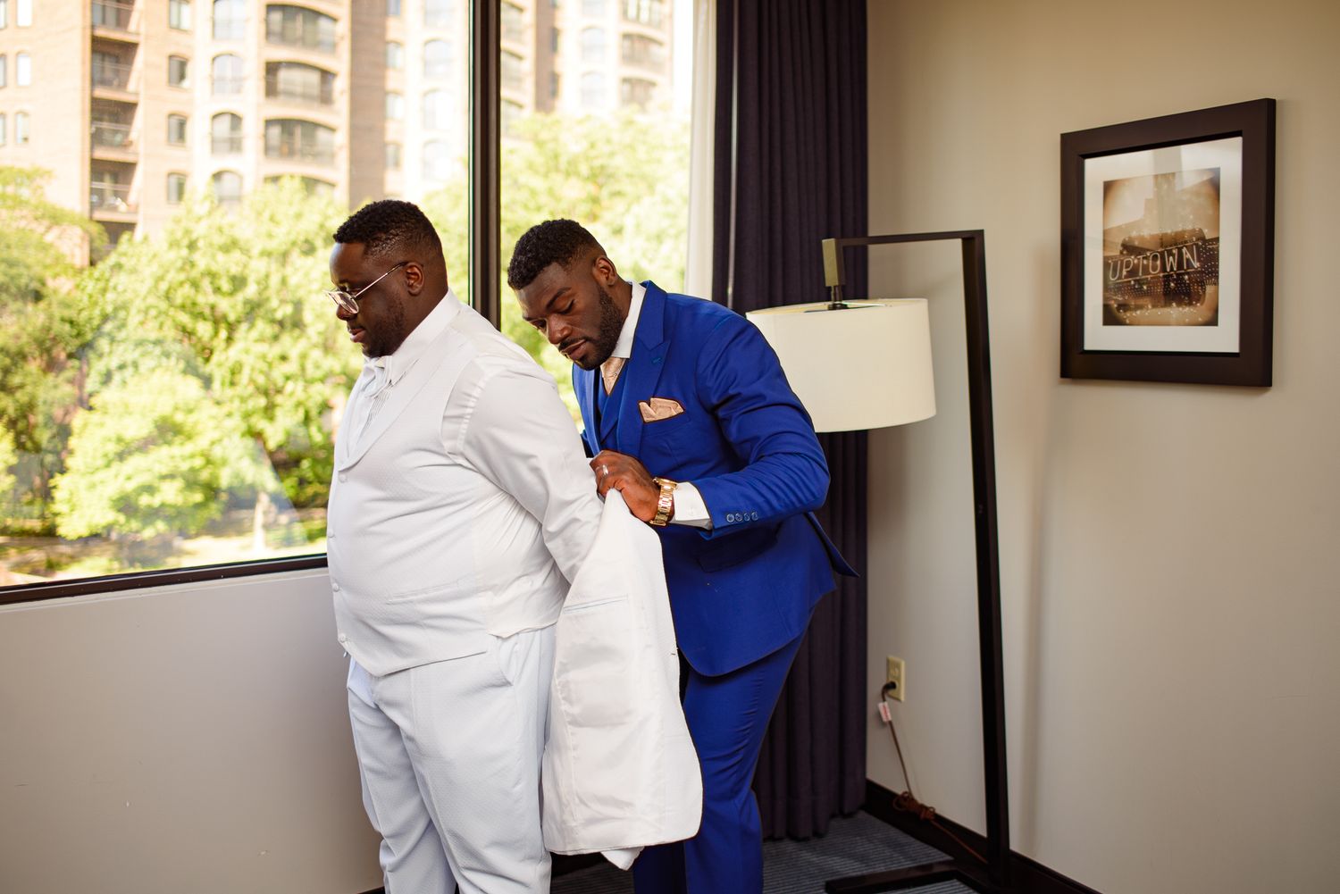 Two people in contrasting white and blue suits interacting in hotel room.