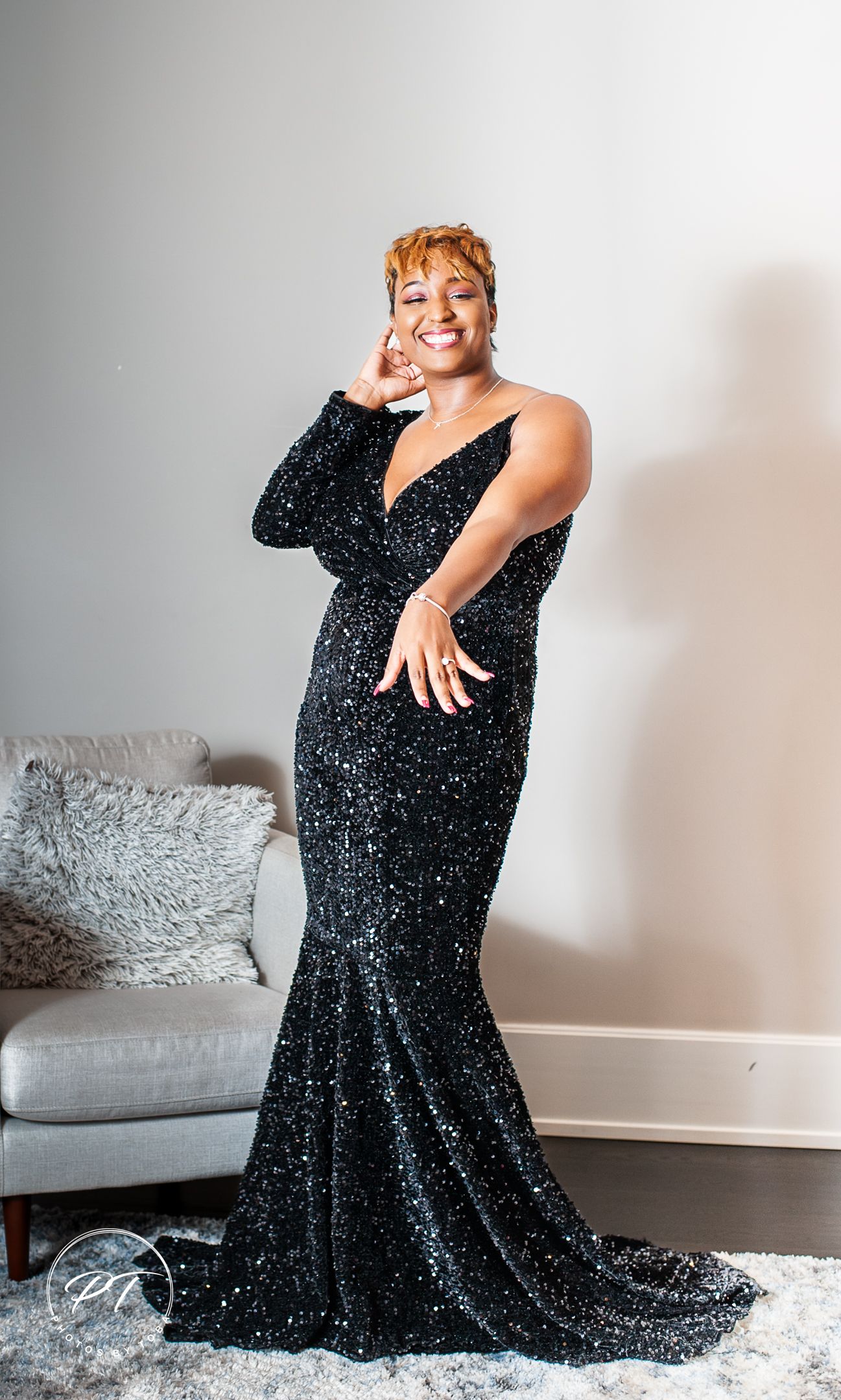 Glamour portrait in sparkly black evening gown against light studio background.