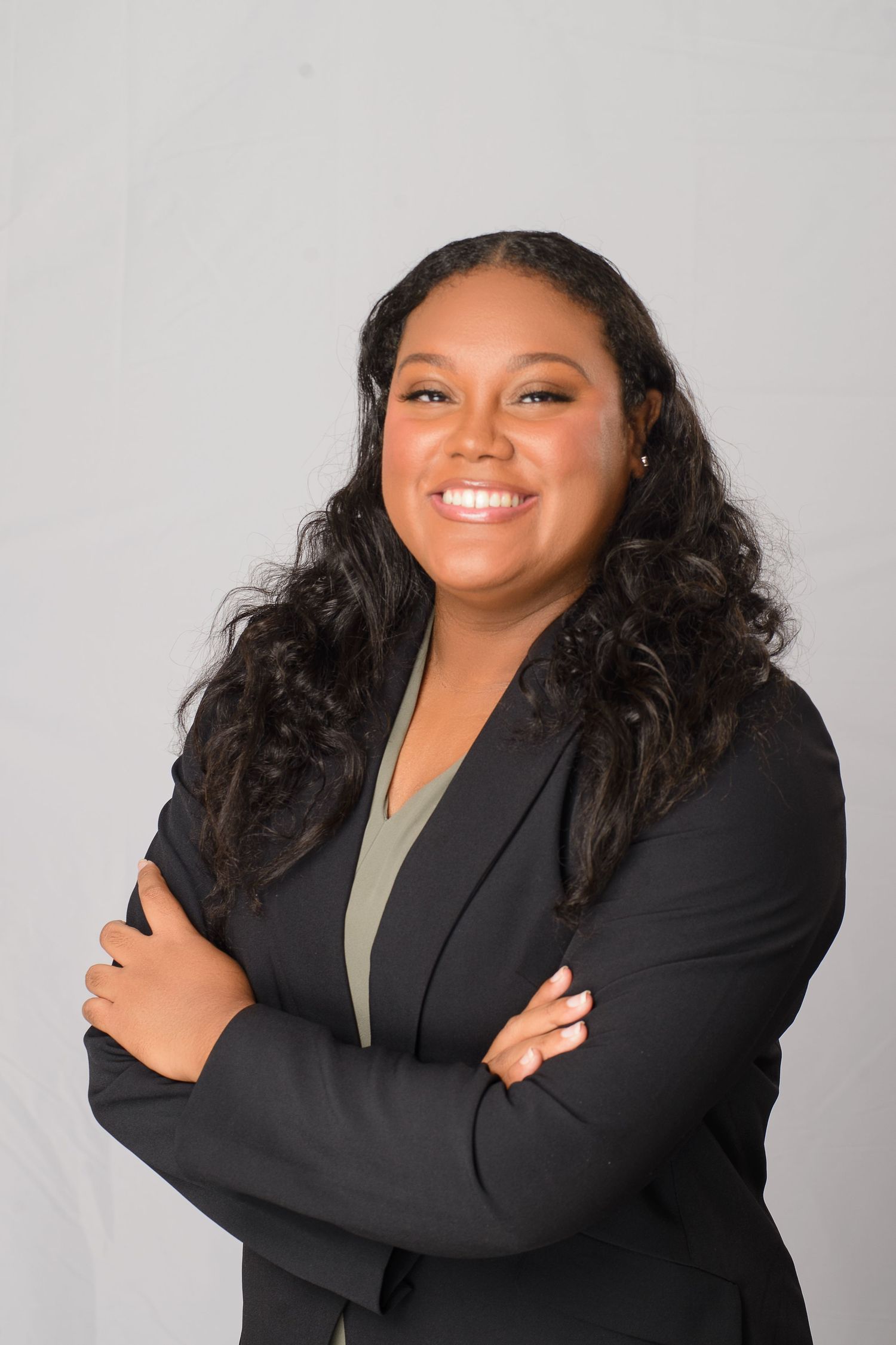 Professional portrait series showing warm expressions while wearing a black blazer and olive top against a gray background.