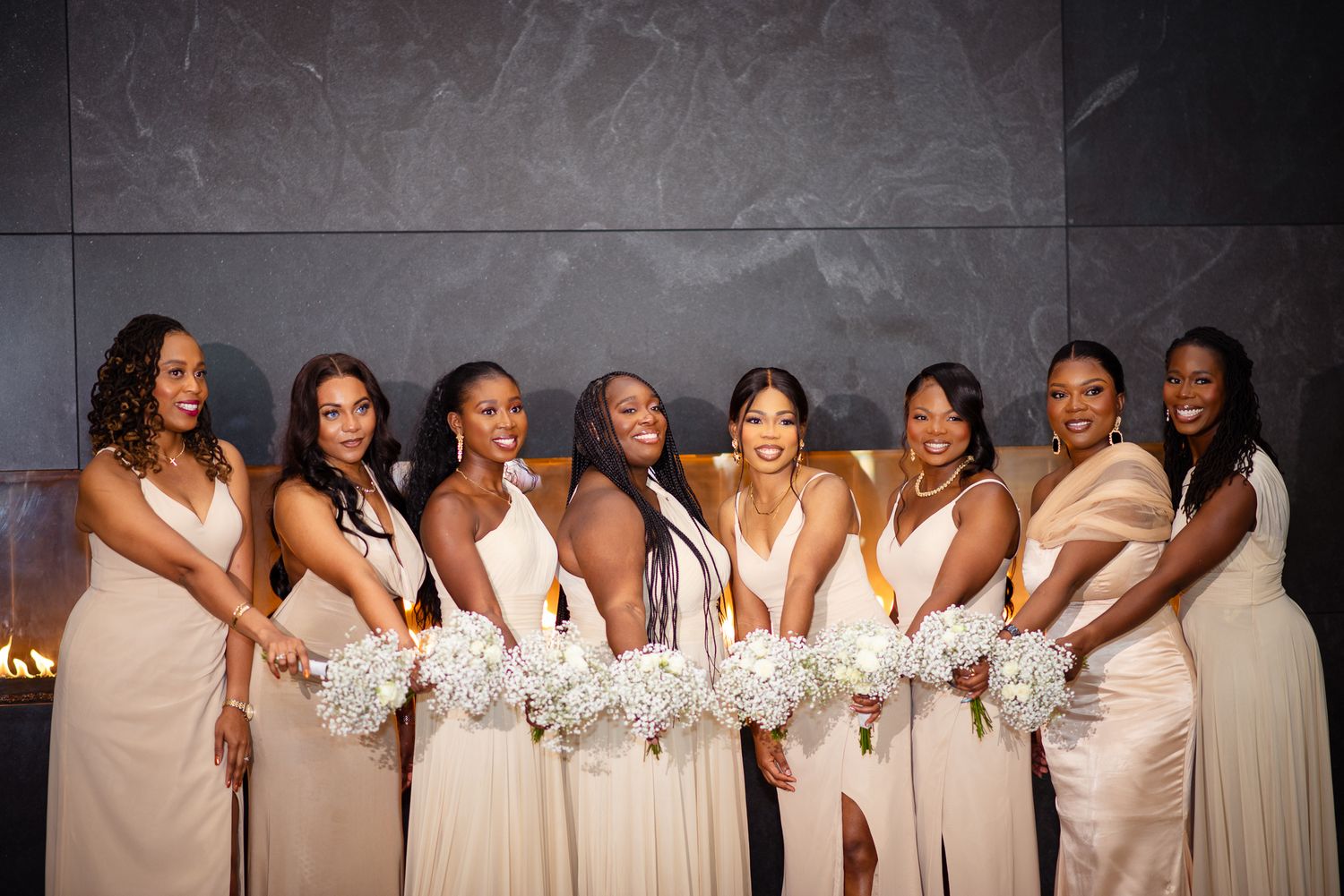 Wedding party group photo with bridesmaids in cream dresses holding white bouquets.