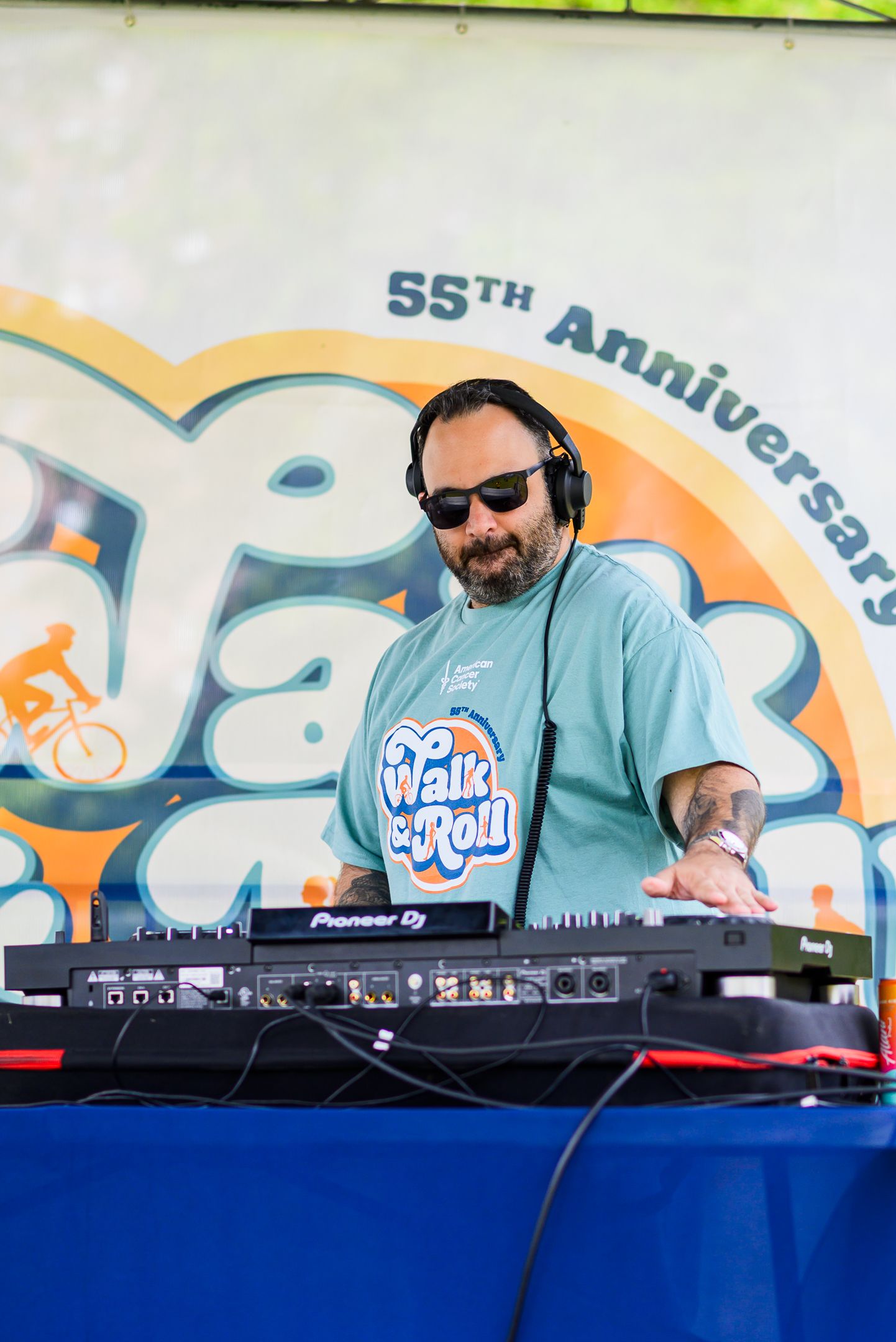 DJ wearing a Walk & Roll 55th Anniversary shirt performs at an American Cancer Society charity fundraising event.