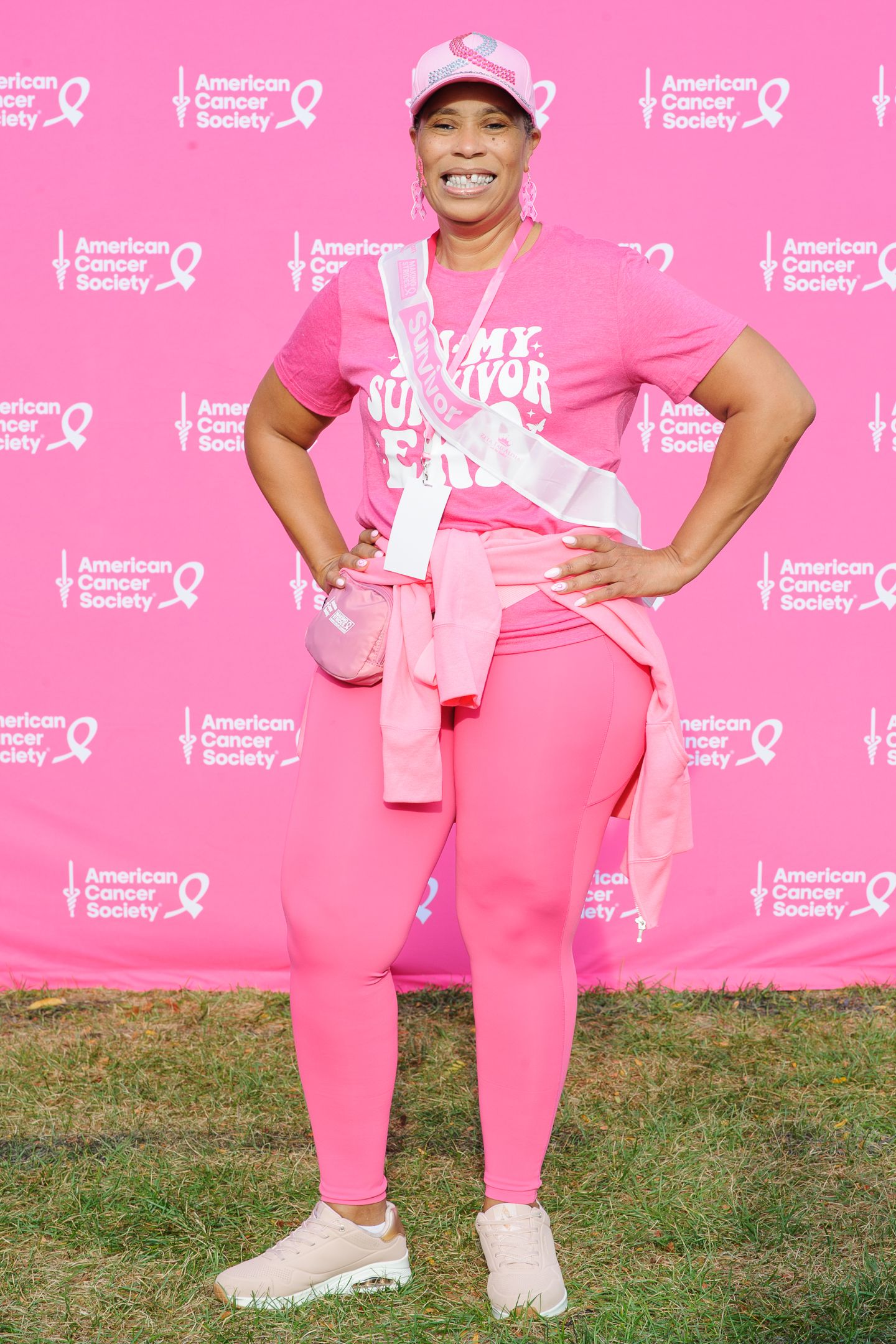 Supporter wearing all pink athletic wear poses confidently at American Cancer Society fundraiser.