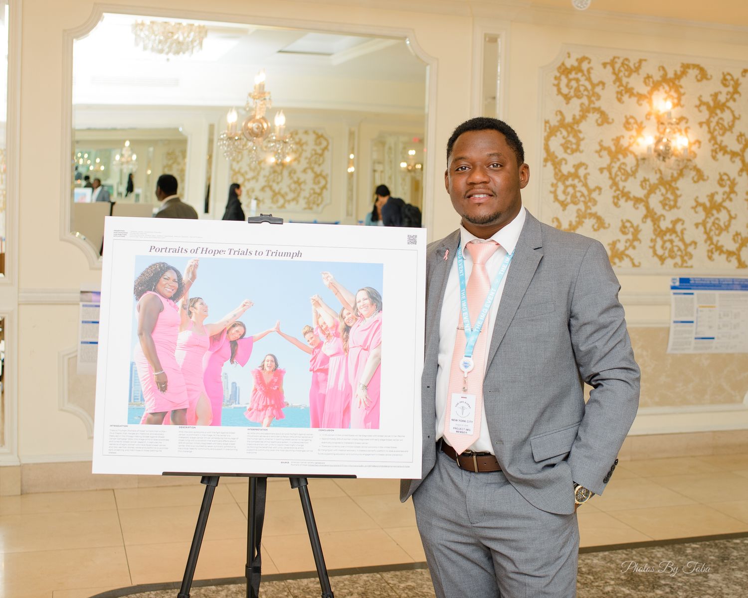 Man in gray suit standing next to a presentation board displaying a colorful photo at a formal event.