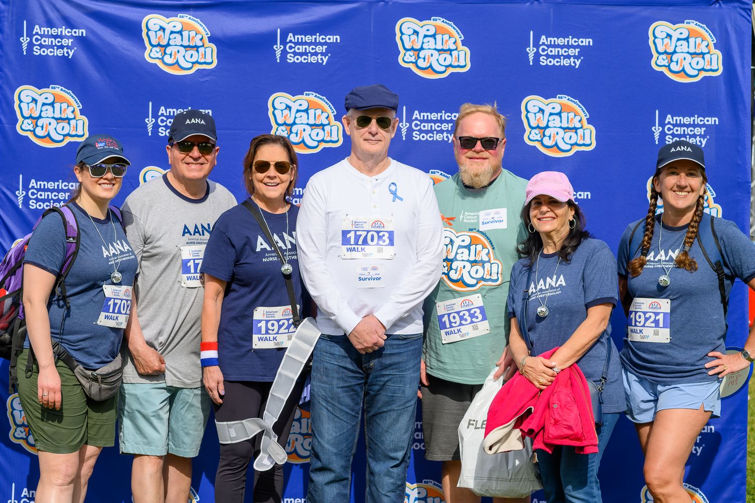 Group of seven smiling volunteers in blue AANA shirts at American Cancer Society Walk and Roll charity event.
