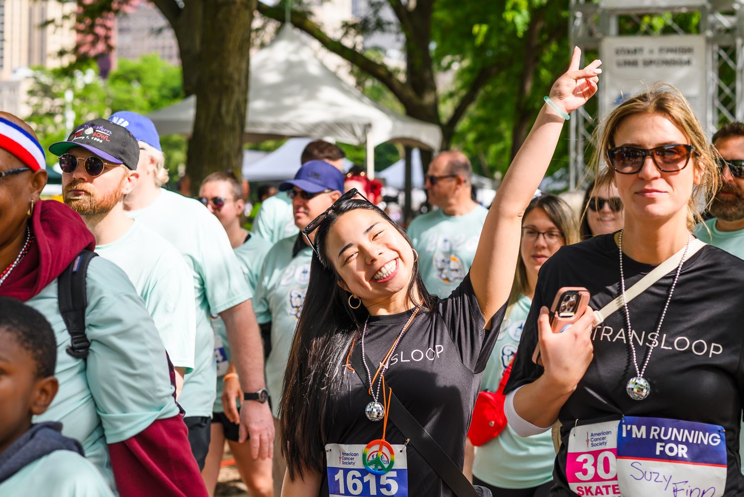 Smiling runners wearing Transloop shirts celebrate at American Cancer Society charity race event.