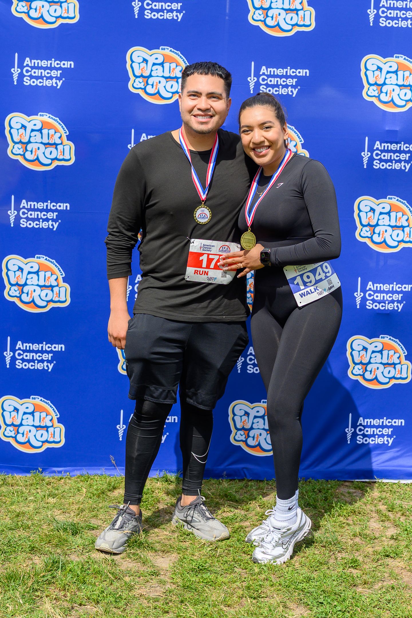 Couple wearing finisher medals pose at American Cancer Society Walk and Roll Chicago race backdrop.
