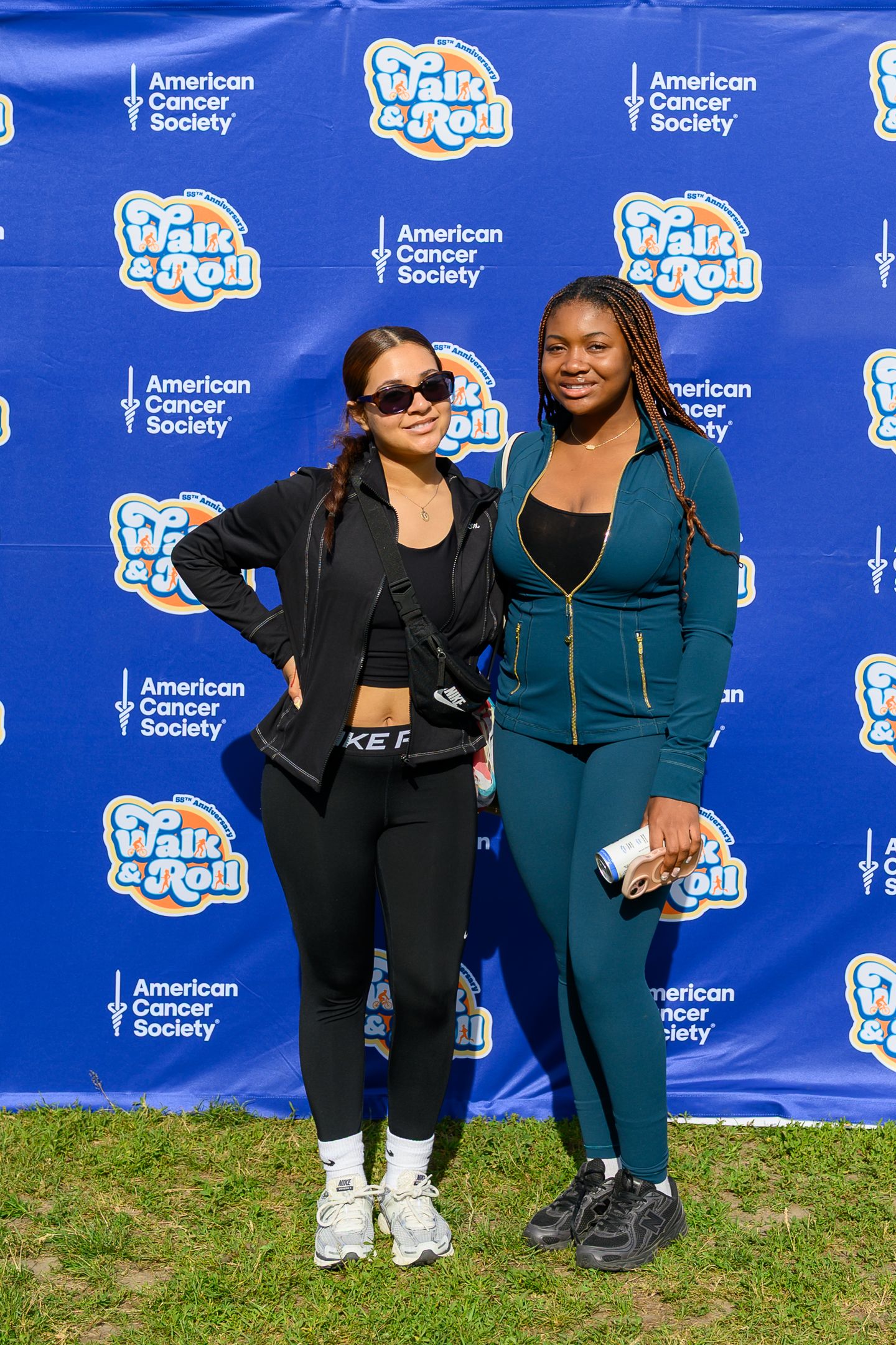 Two women pose together at American Cancer Society Walk & Roll event backdrop.