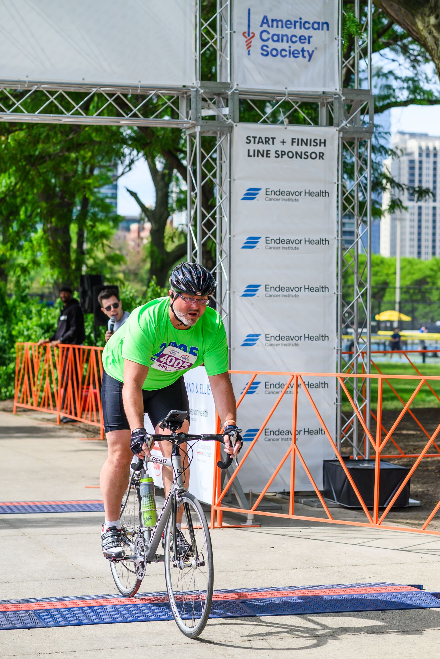 Cyclist in green shirt crosses finish line at American Cancer Society race sponsored by Endeavor Health.