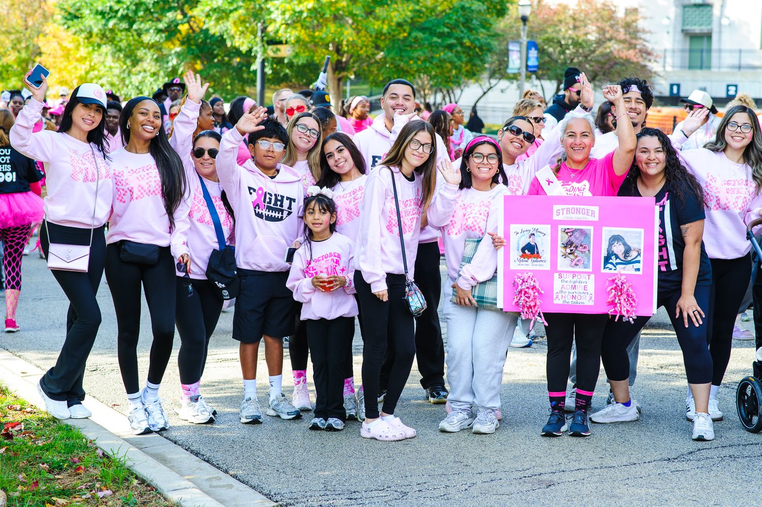 Large group of participants wearing pink and white attire gather at an outdoor breast cancer awareness event.