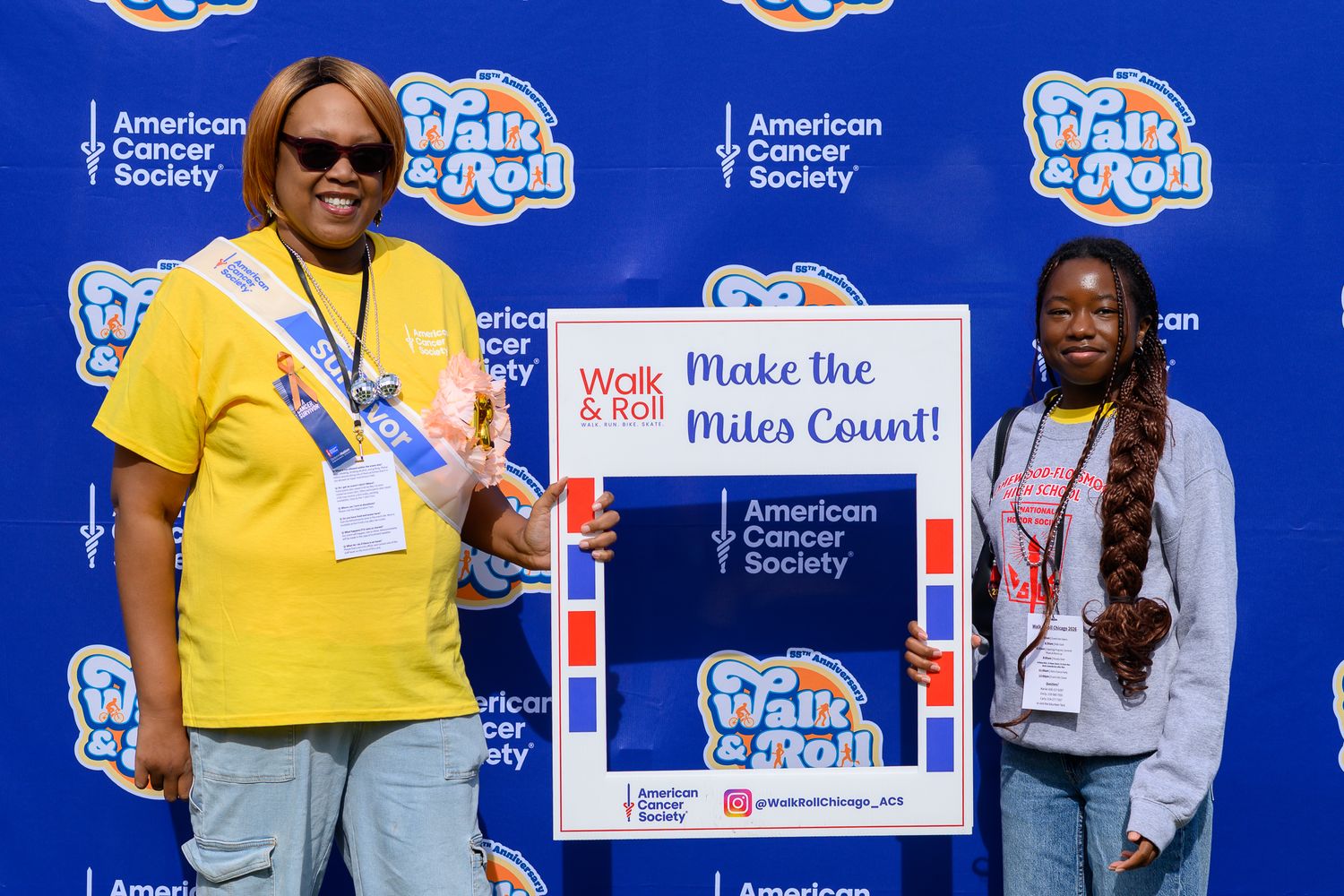 Two women holding Make the Miles Count sign at American Cancer Society Walk and Roll fundraising event.