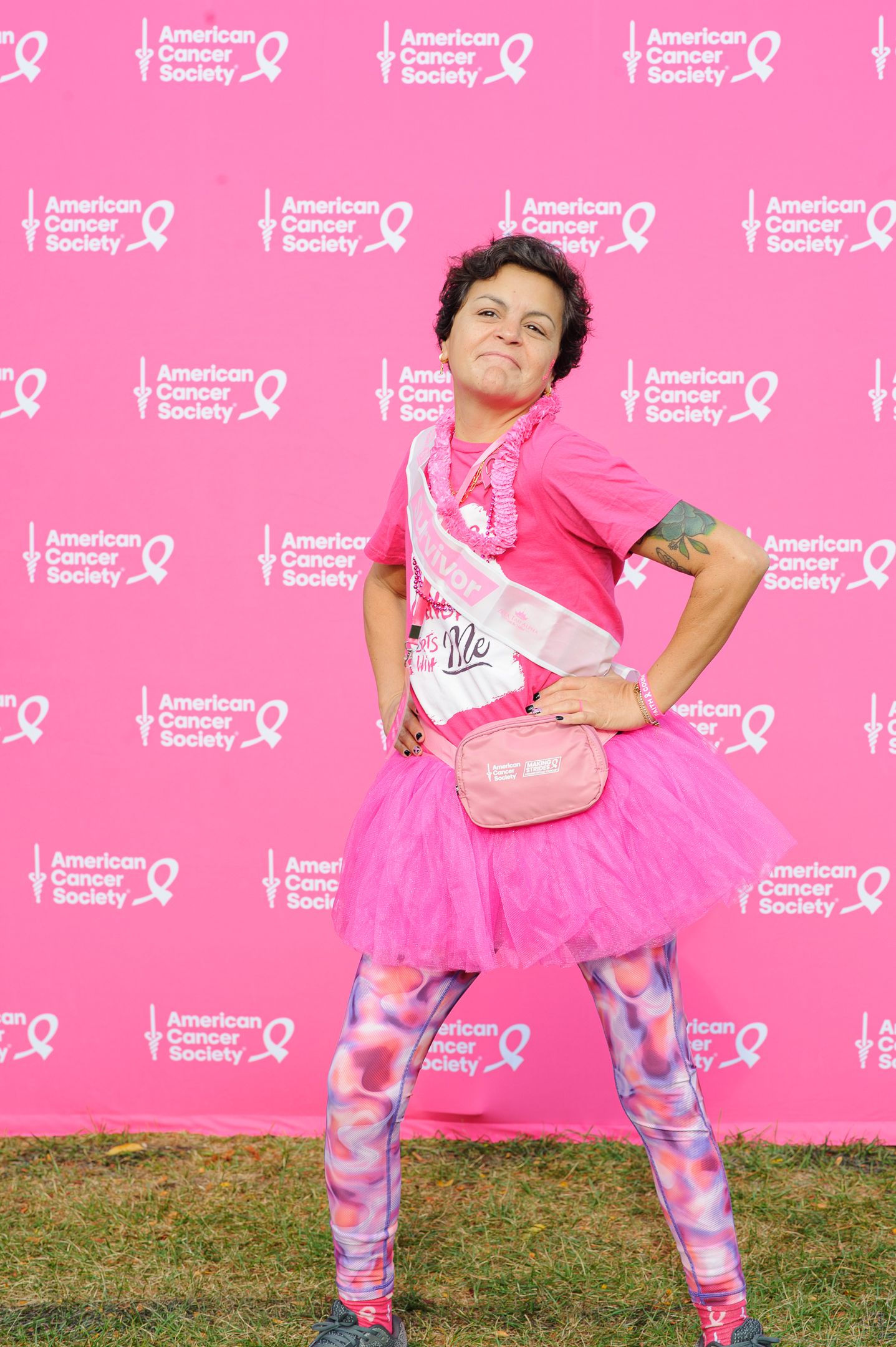 Person in pink tutu and patterned leggings strikes playful poses at cancer awareness event.