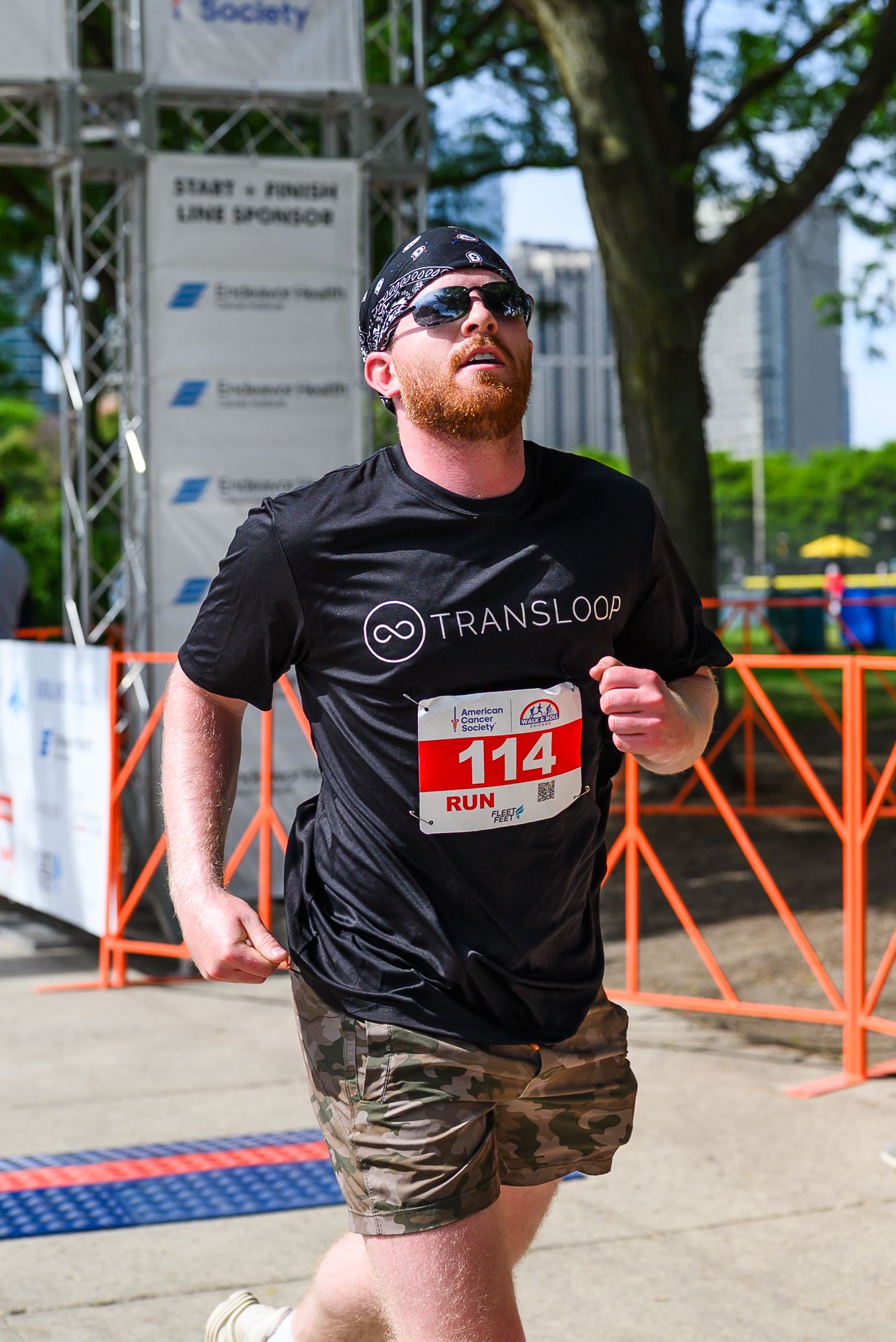 Bearded man in Transloop black shirt crosses finish line at American Cancer Society Walk & Roll Chicago run.