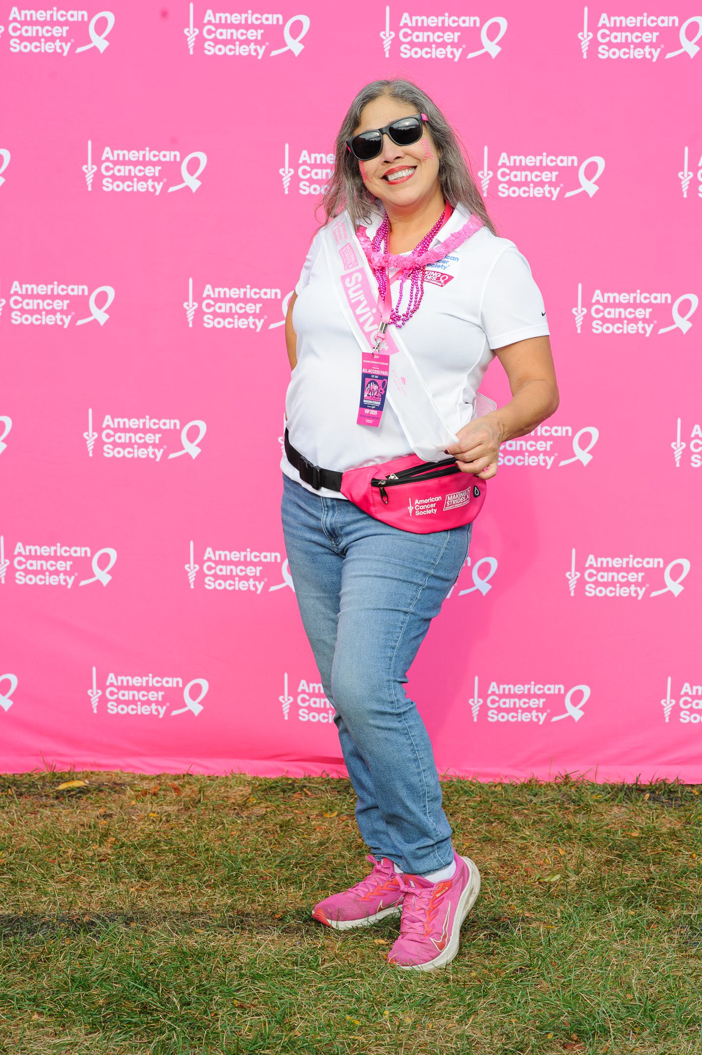 Participant wearing sunglasses and pink accessories smiles at American Cancer Society event.