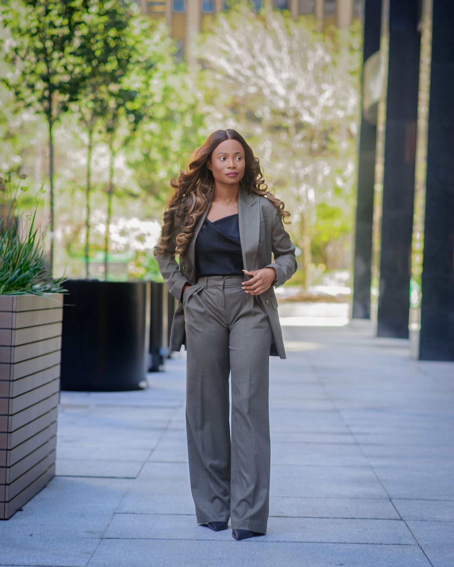 Professional walking in grey business suit outdoors near modern office building.