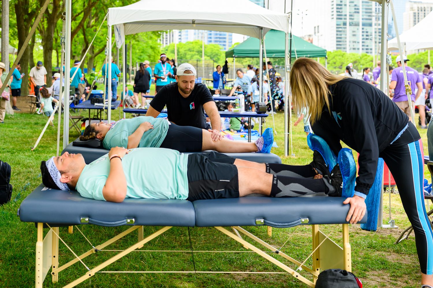 Post-race massage therapists provide muscle recovery treatment to participants at outdoor charity event.