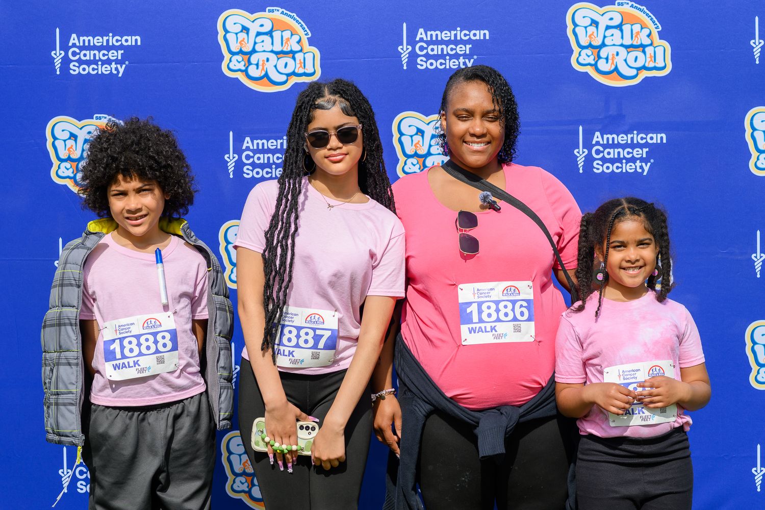 Family of four in matching pink shirts pose together at American Cancer Society Walk & Roll Chicago event.