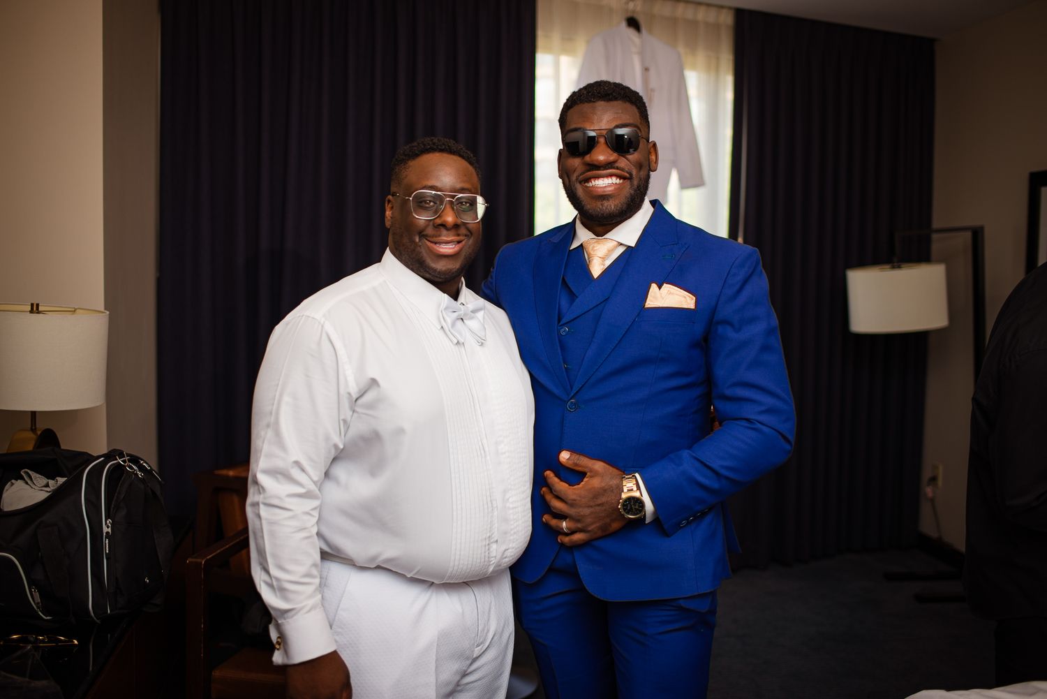 Two people in formal attire stand together smiling at a professional event.