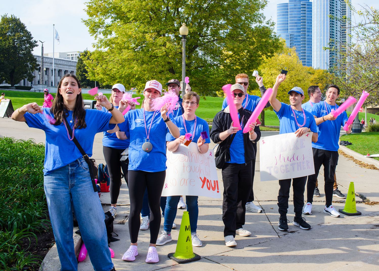 A group in matching blue shirts participates in an outdoor event with signs and colorful accessories in a park setting.