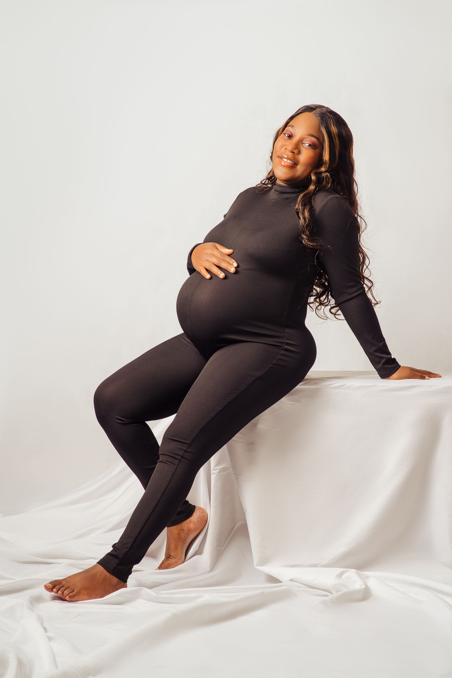 Artistic maternity portraits showing pregnancy silhouette on white fabric backdrop.