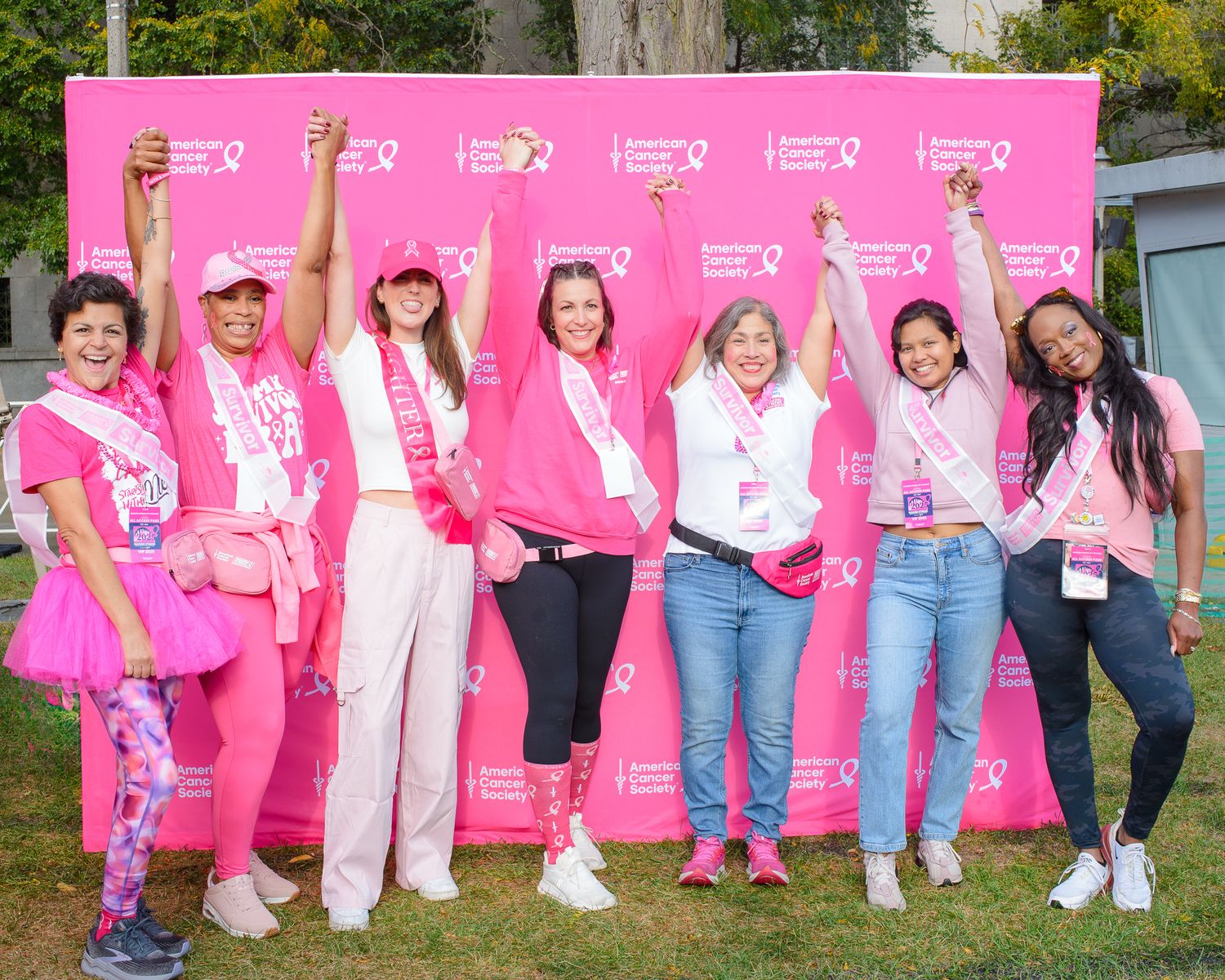 Large group photo of participants in pink attire at American Cancer Society outdoor event.