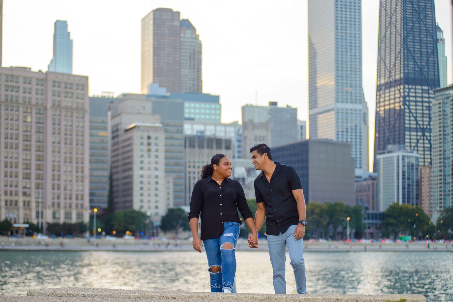 Couple holding hands walking by Chicago skyline waterfront on a sunny day.