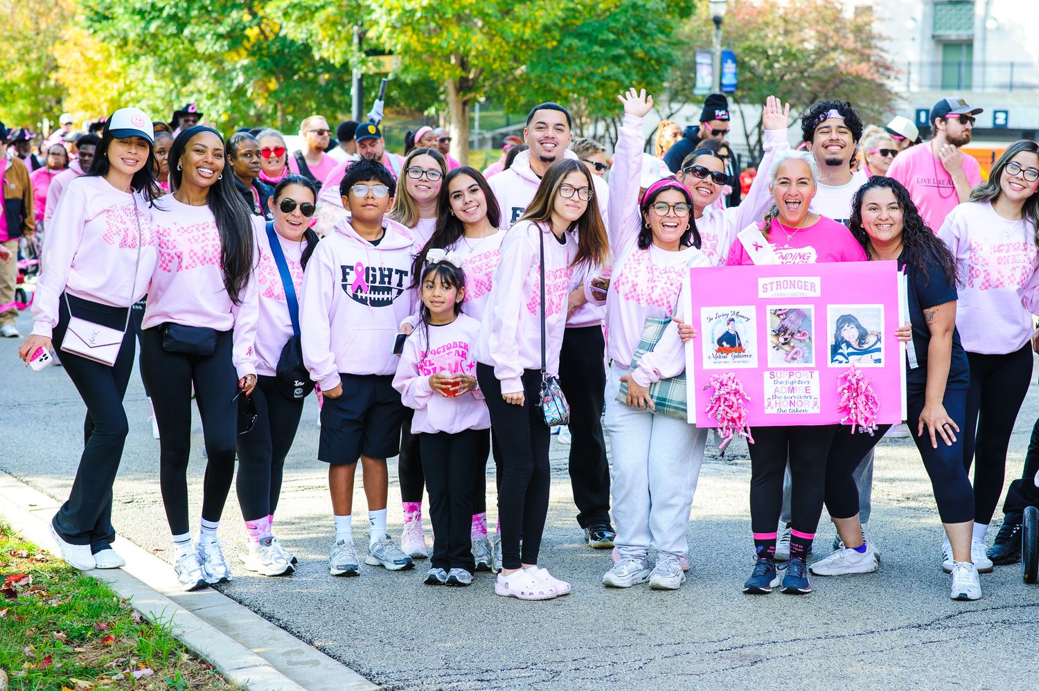 Group of participants wearing pink and white shirts walking together during a breast cancer awareness event outdoors.