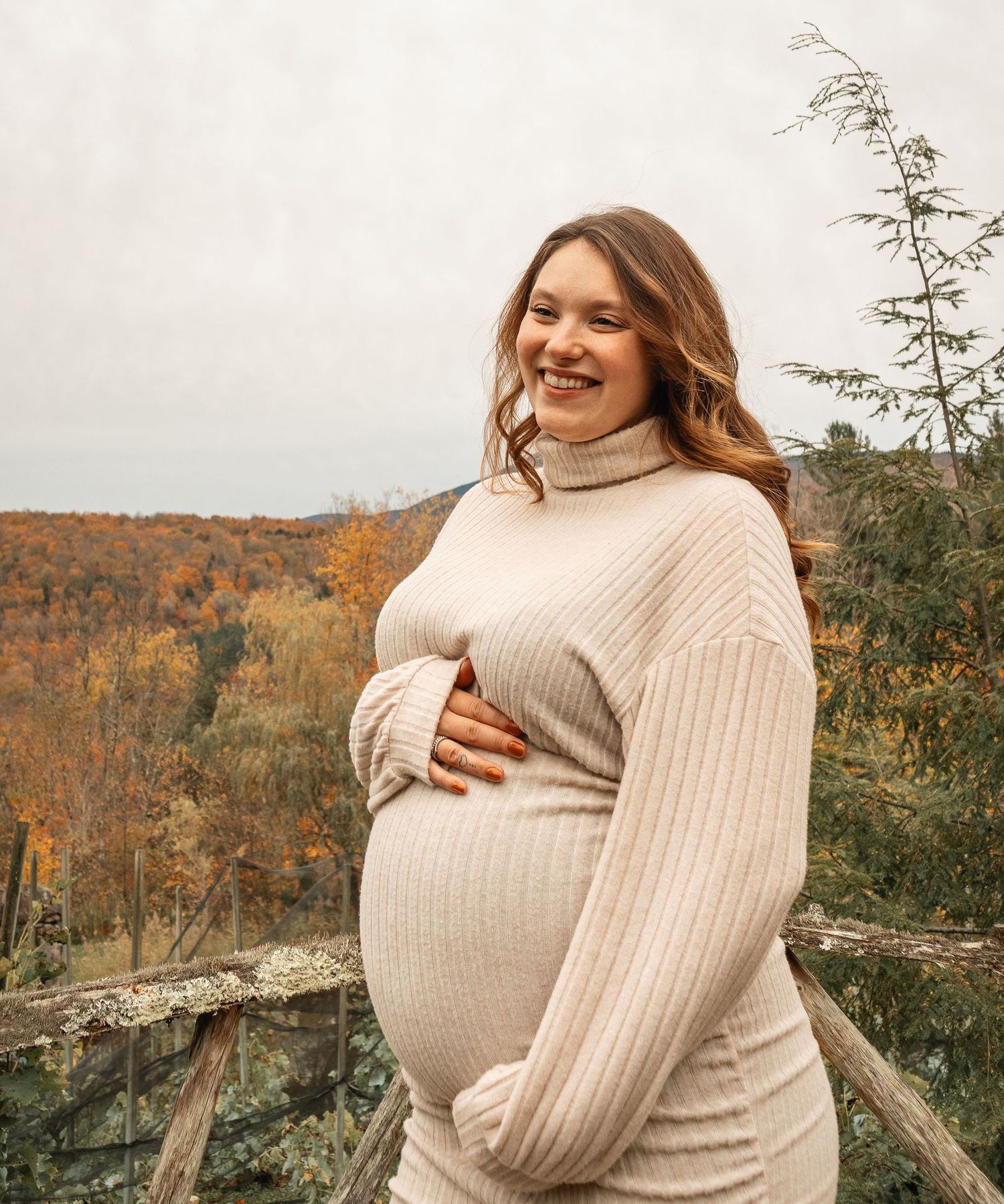 Séance photo de maternité en extérieur montrant une future maman souriante au cœur des couleurs d'automne en Montérégie.