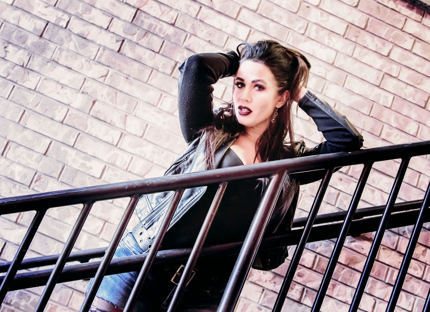 Fashion portrait on metal stairs with dramatic angle and urban background.