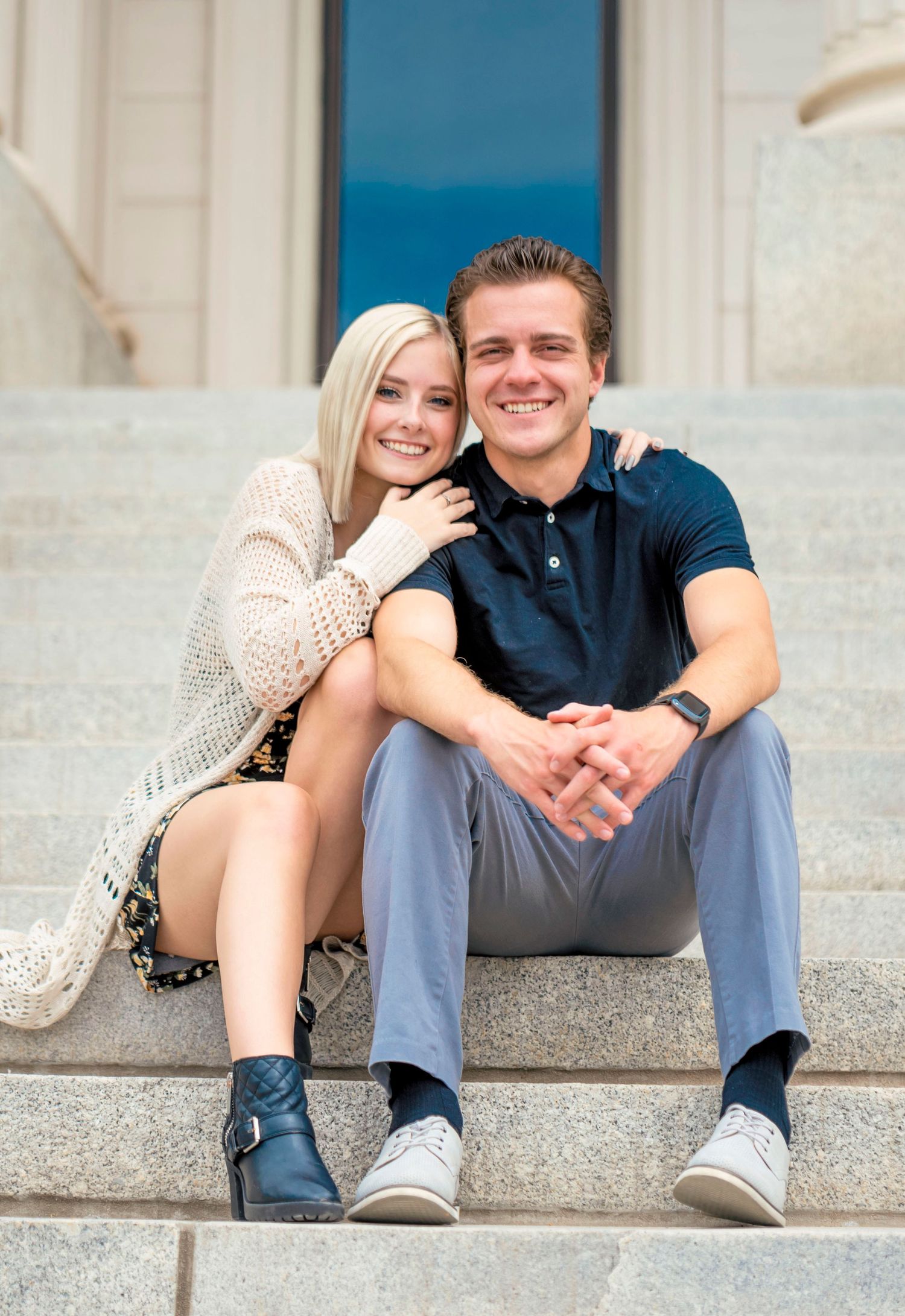 Couple sitting close together on stone steps in casual attire.