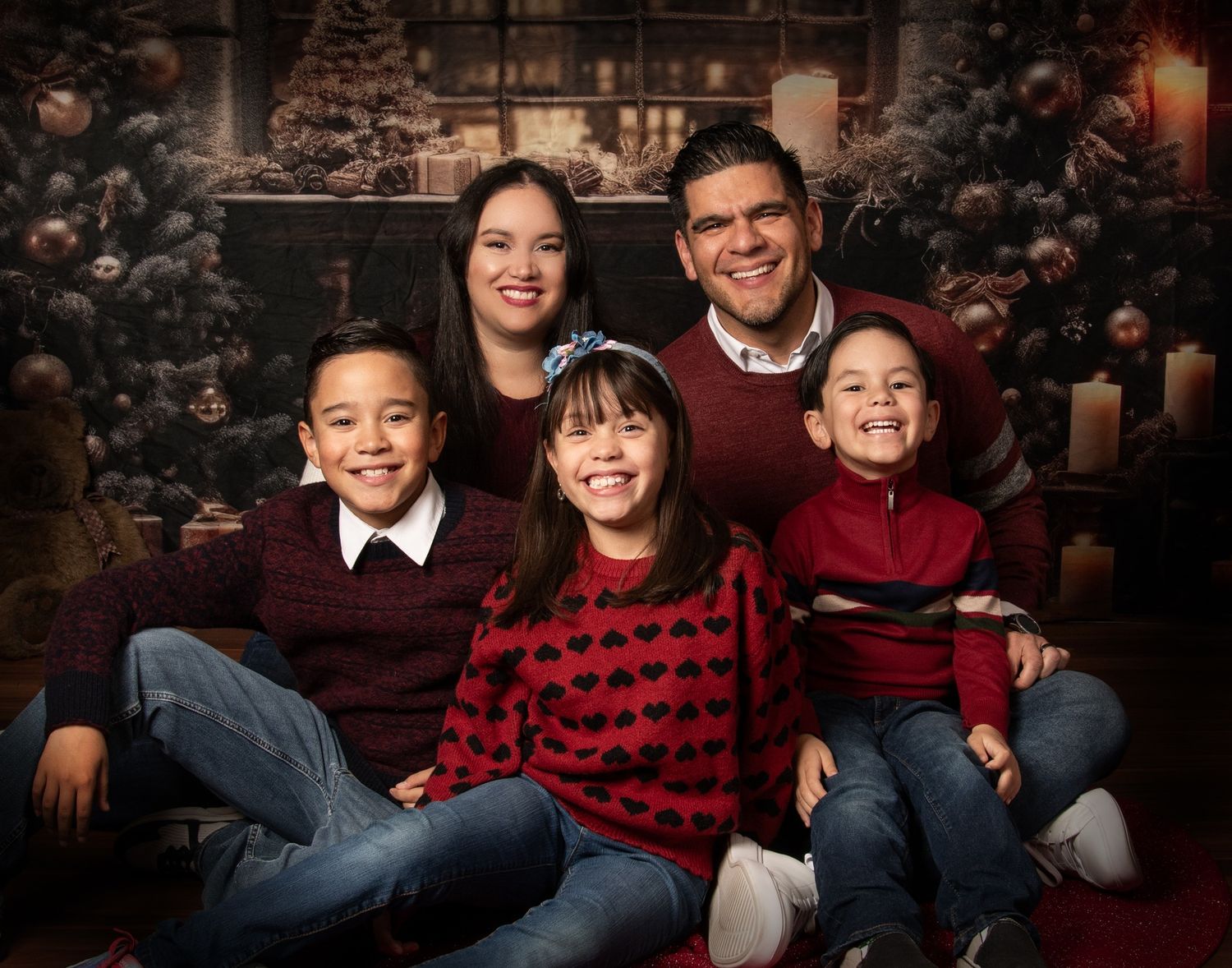 A family wearing coordinating red and black buffalo plaid shirts poses together for holiday portraits.