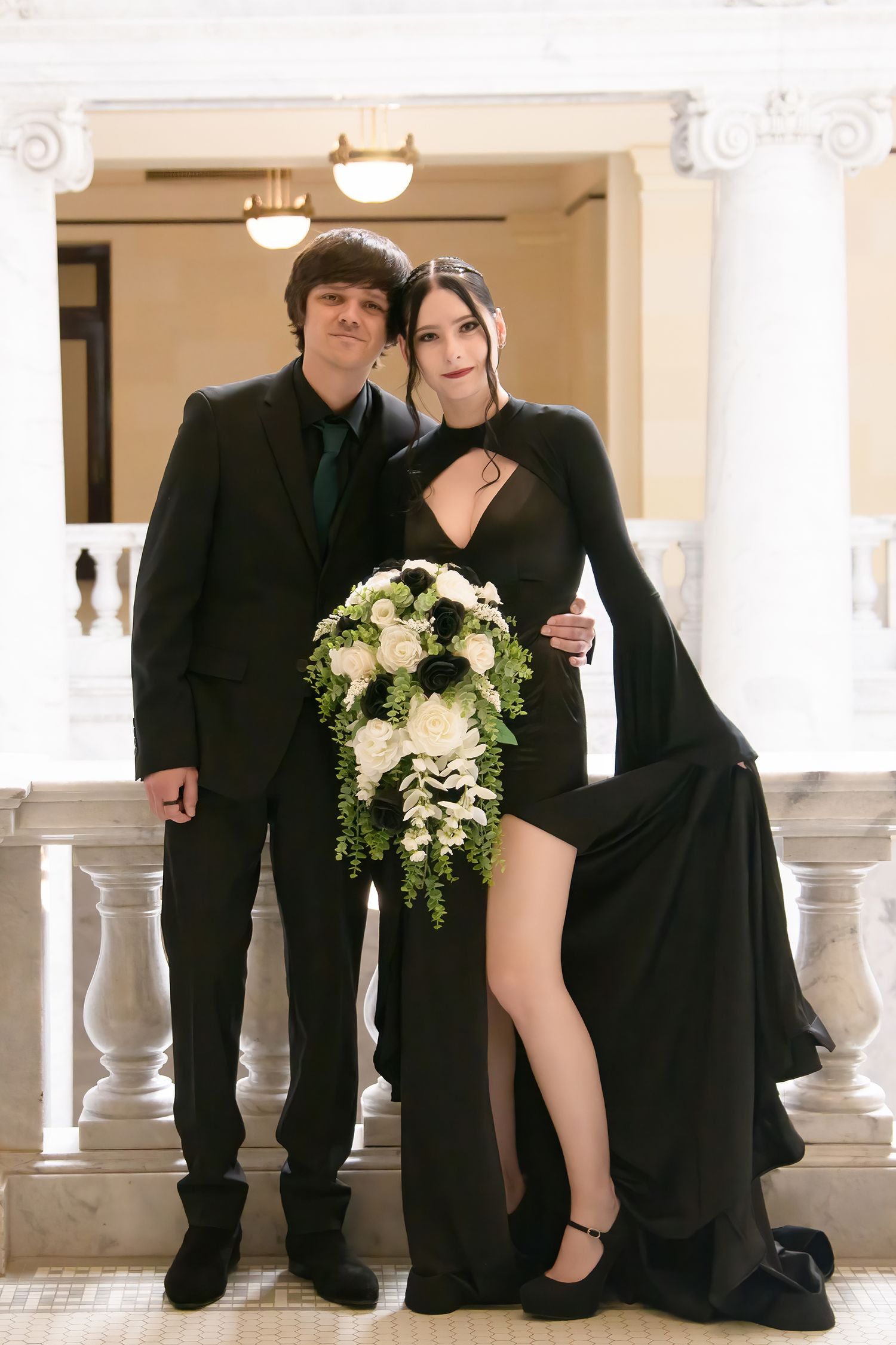Intimate posed wedding portraits of couple in black attire sitting on ornate marble staircase.