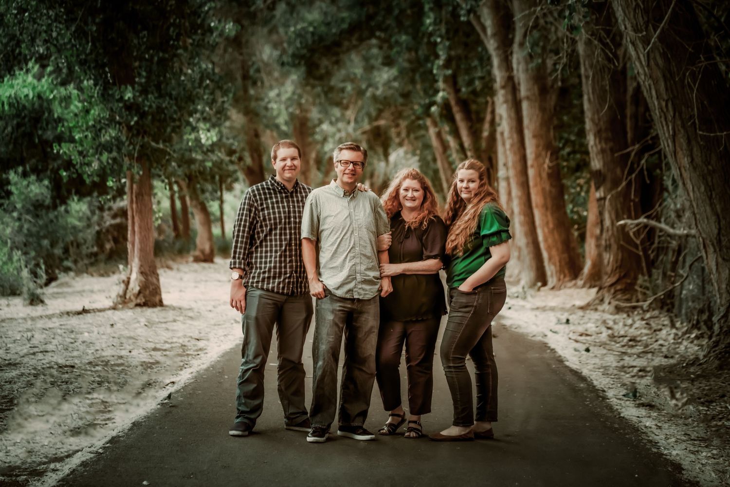 Family group standing together on a wooded path for a casual outdoor portrait.