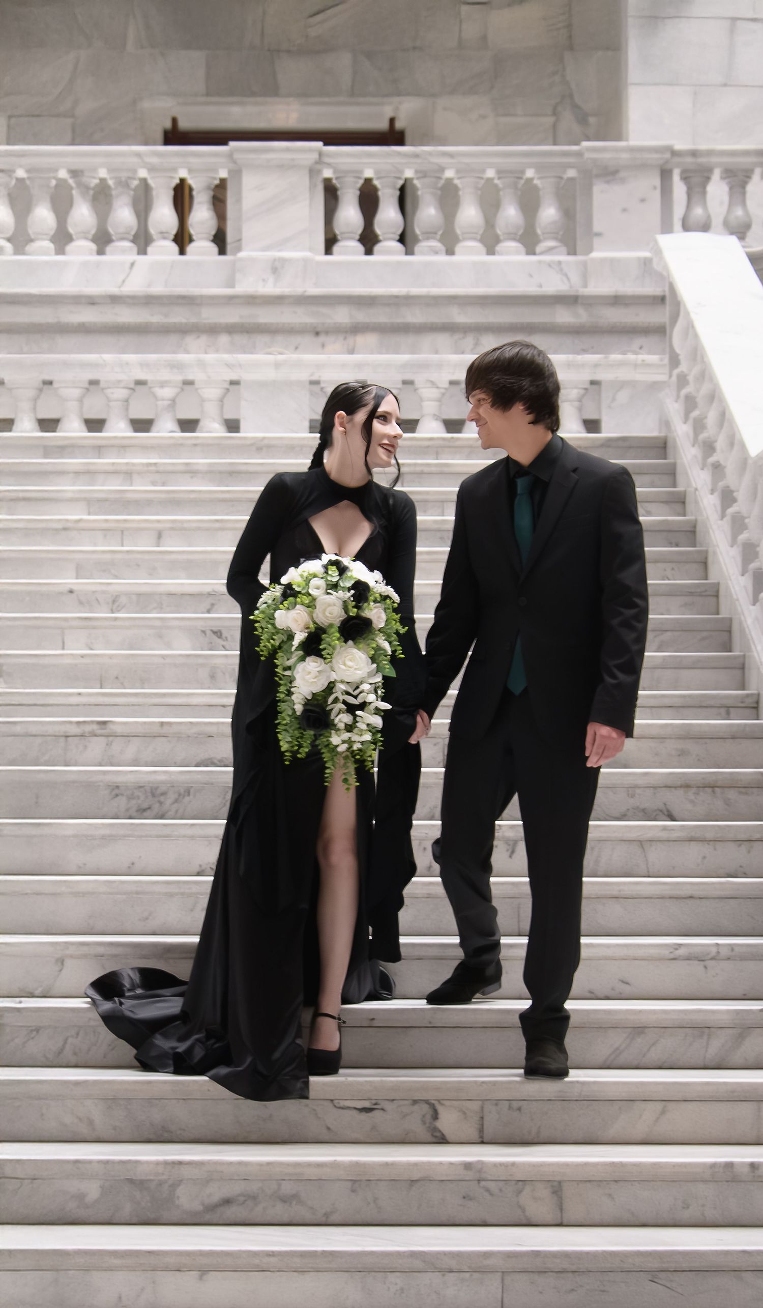A couple in wedding attire poses on grand marble steps in a series of romantic black and white photographs.
