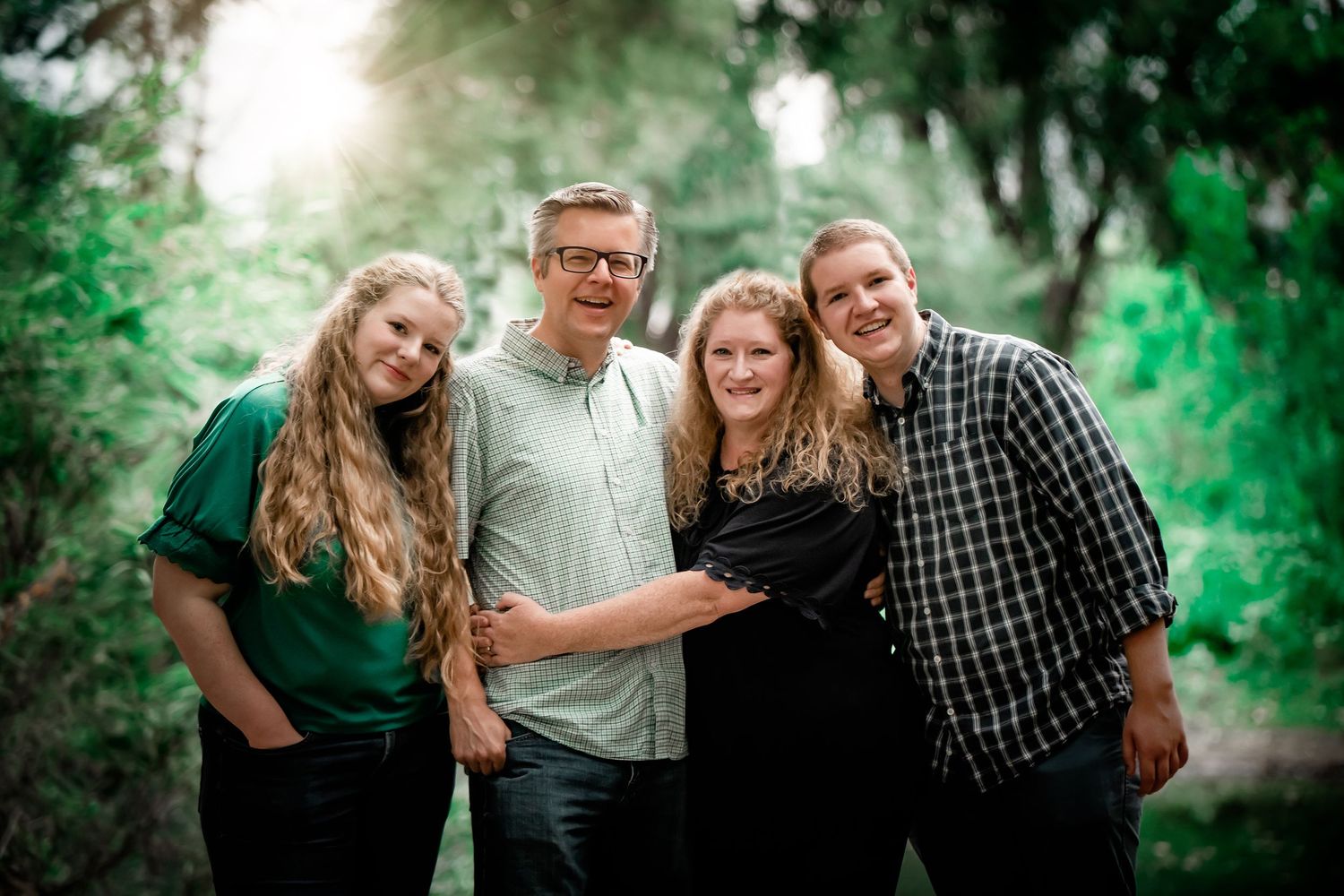 Casual outdoor family portrait in a lush green park setting.