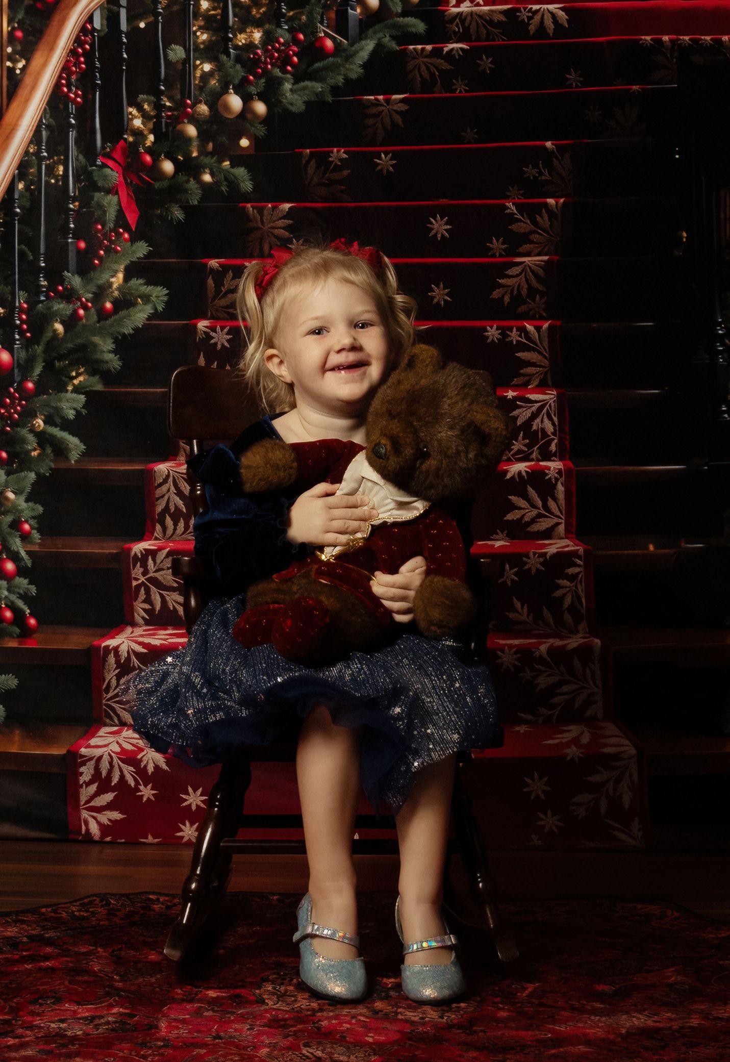 A festive holiday portrait on red-carpeted stairs decorated with garland, lights and snowflakes.