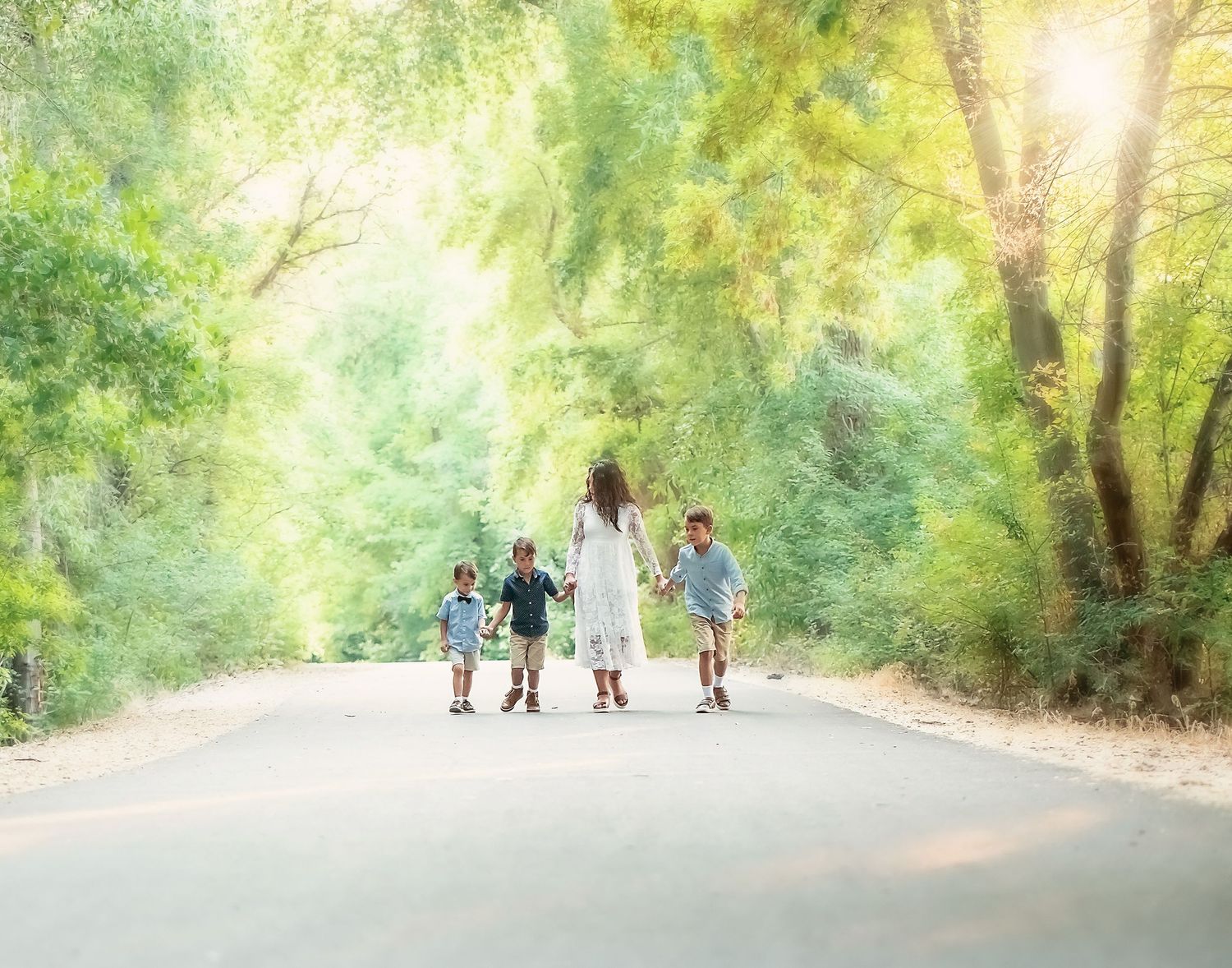 Silhouetted figures walking together on a sunlit tree-lined path in a dreamy summer setting.