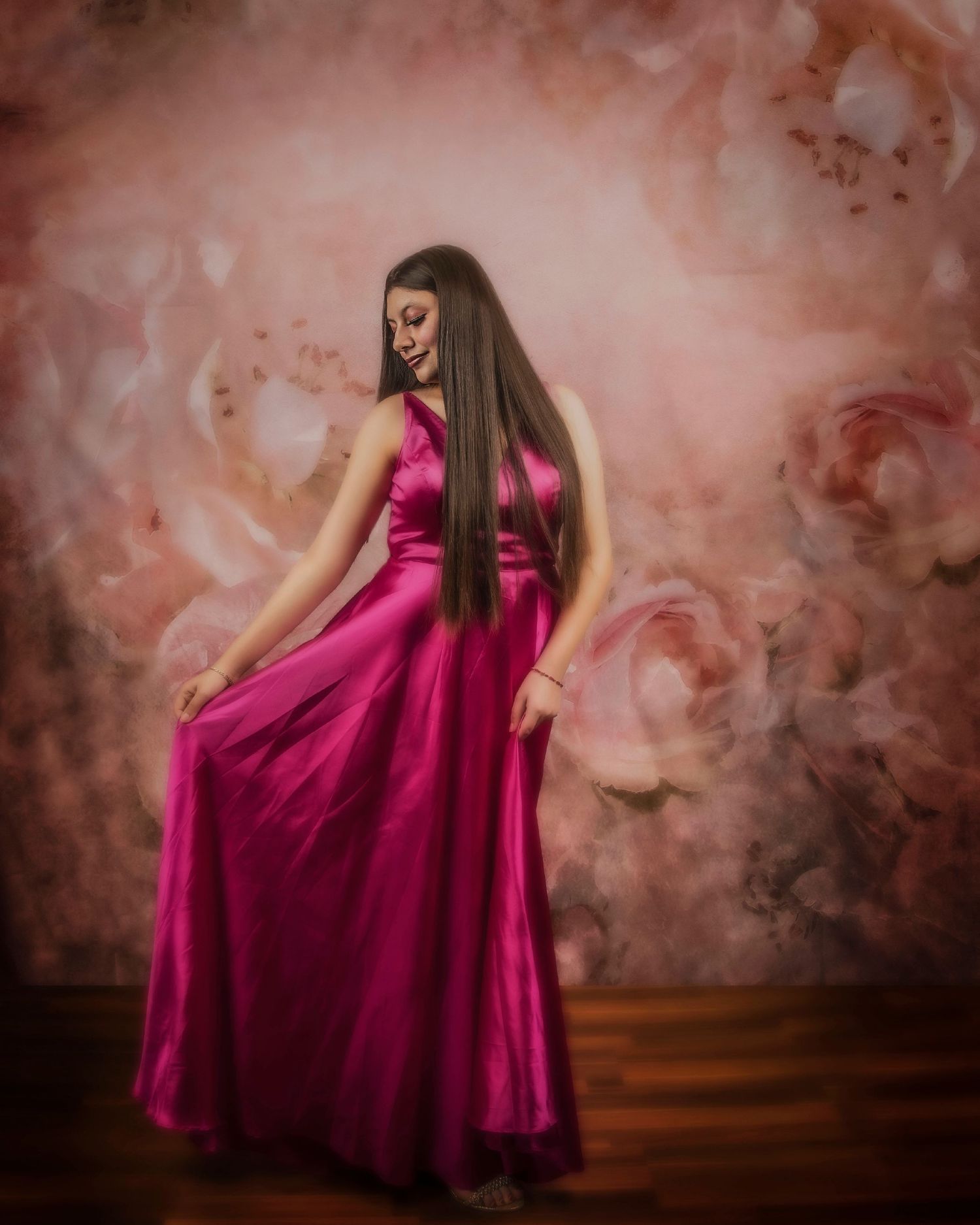 A person in a flowing magenta evening gown poses elegantly against a dreamy brown smoke effect background.