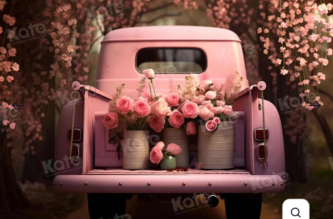 Vintage pink pickup truck bed filled with fresh pink roses and rustic containers under blooming cherry trees.